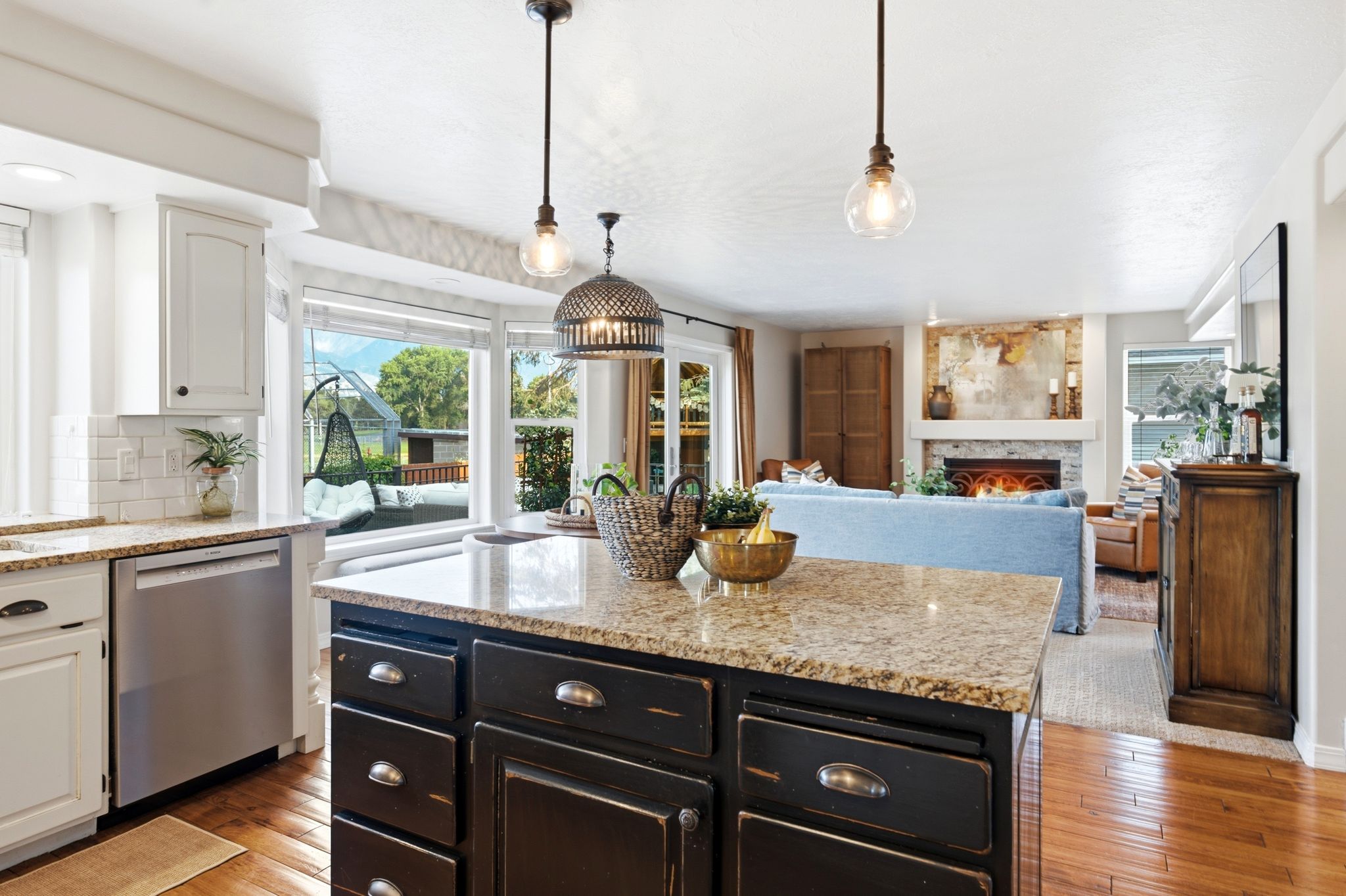 Kitchen island with granite countertop, dark cabinetry, and pendant lighting