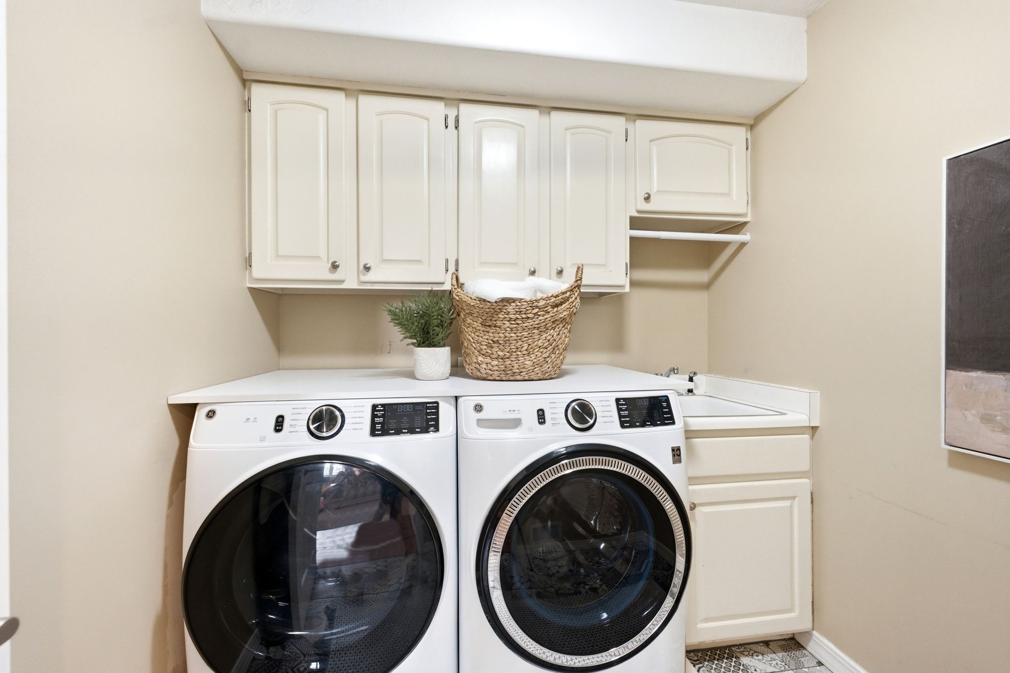 Laundry area featuring white cabinetry, a built-in sink, and a countertop surface above the appliances