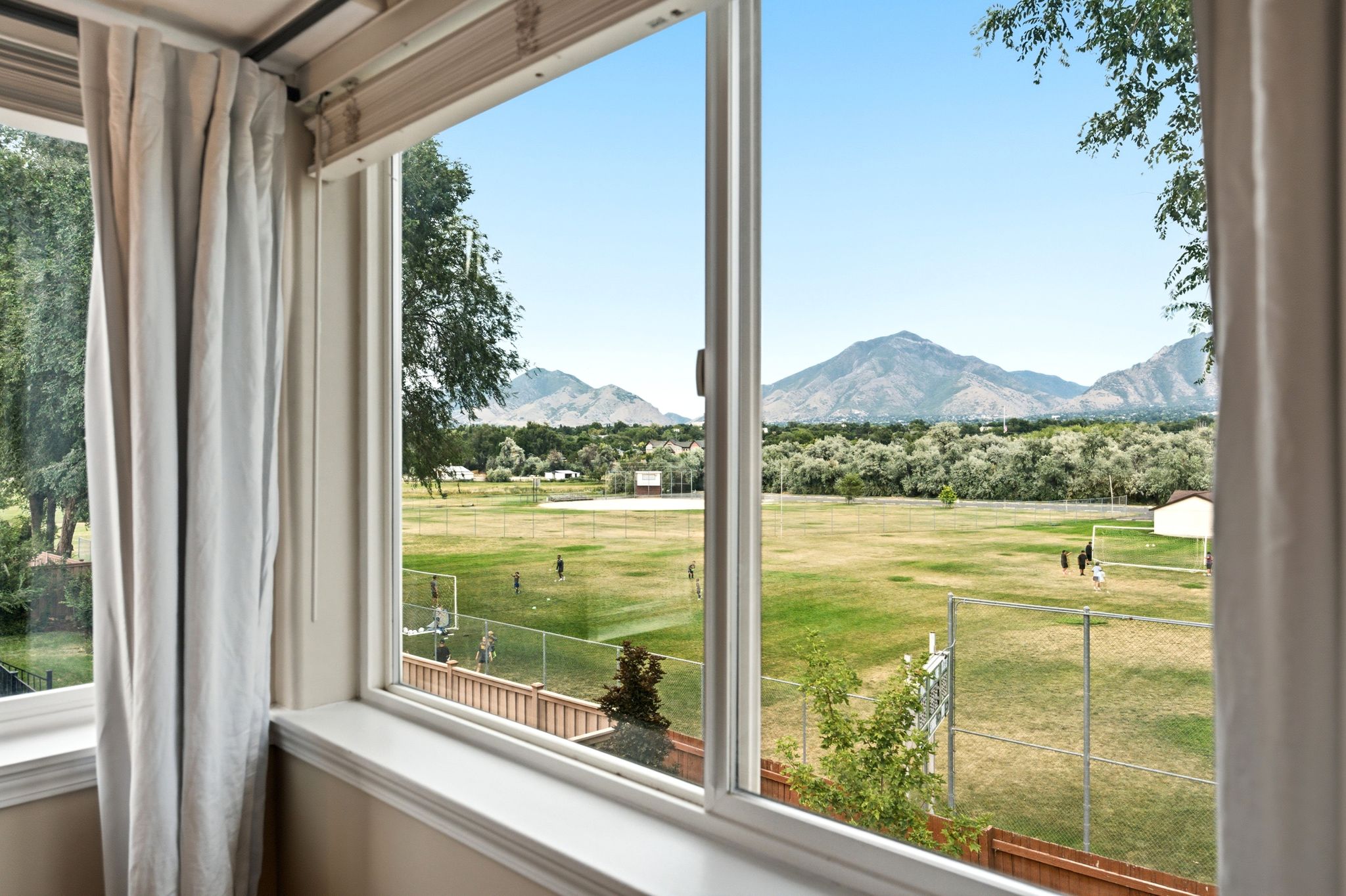 Expansive window offering a sweeping mountain backdrop and open field scenery
