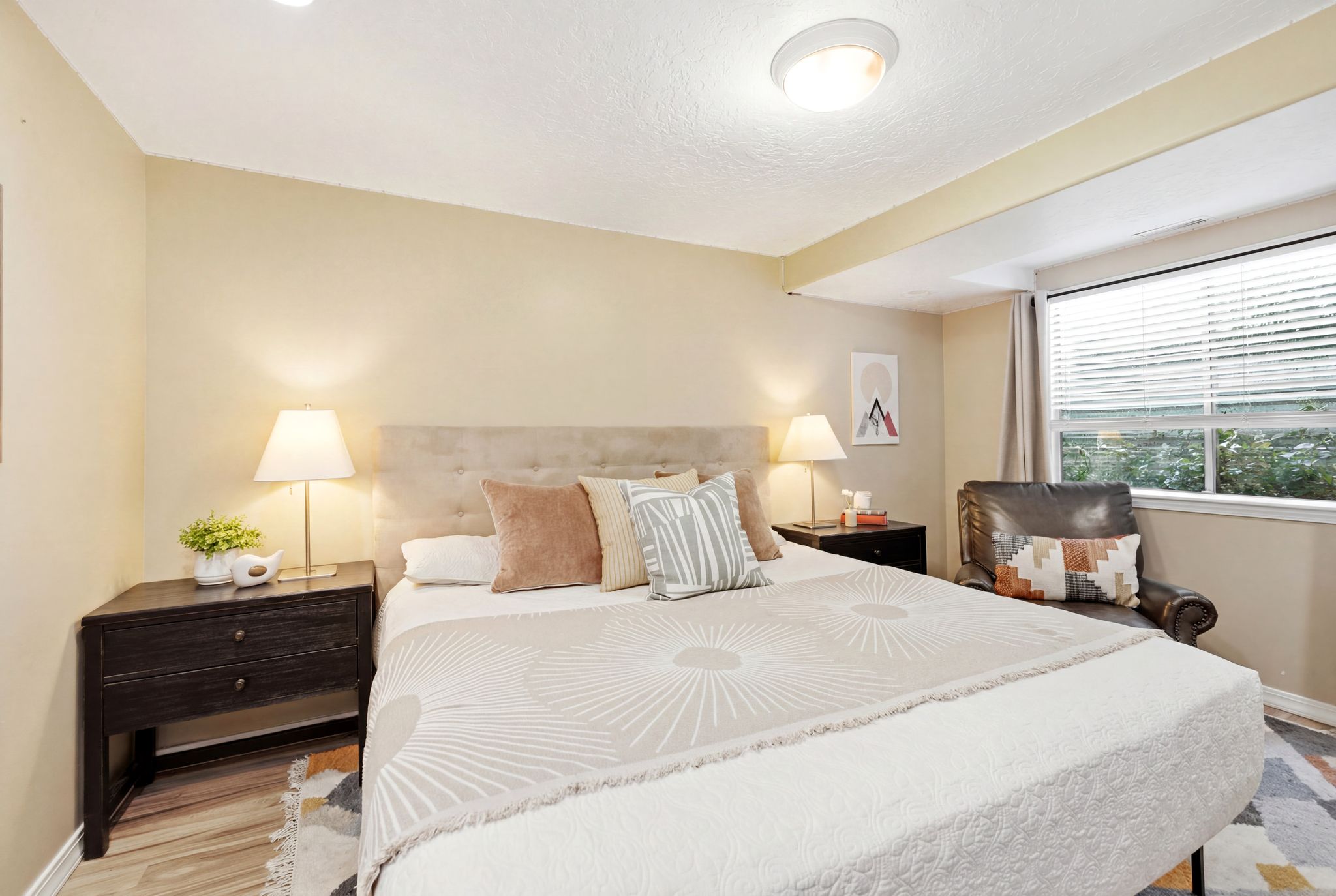 Bedroom featuring a window with blinds, light-toned walls, and wood-finish flooring
