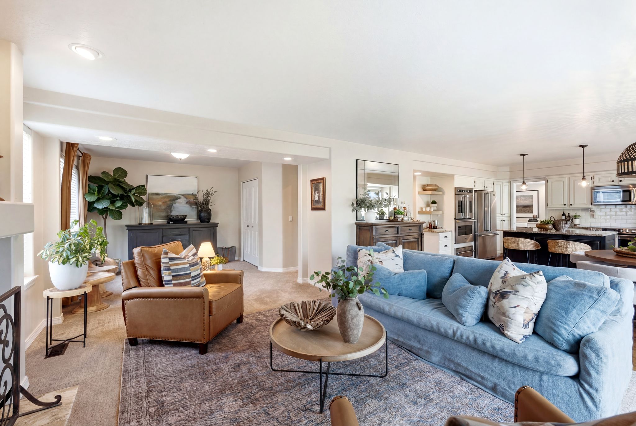 Open-concept living area featuring recessed lighting, a neutral color palette, wood-finish flooring, and a kitchen with white cabinetry and stainless steel appliances
