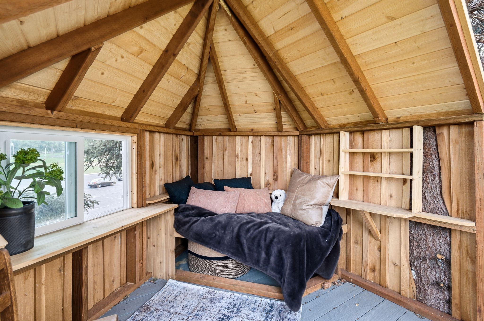 Interior space featuring natural wood paneling, exposed wood beams, a built-in window seat, an operable window, and a built-in shelving unit