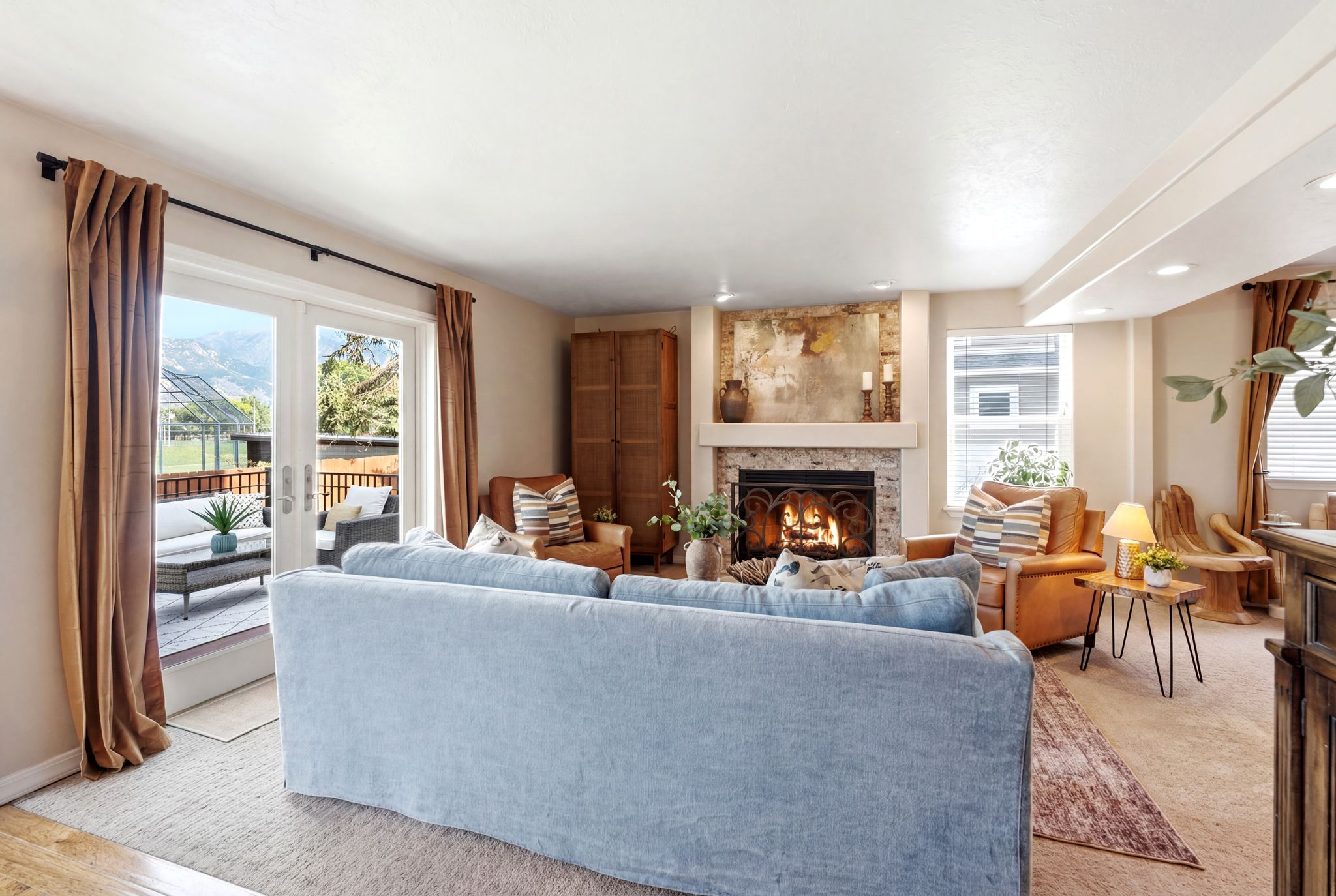 Living area with a stone-clad fireplace and mantel, recessed lighting, and french doors opening to an exterior deck