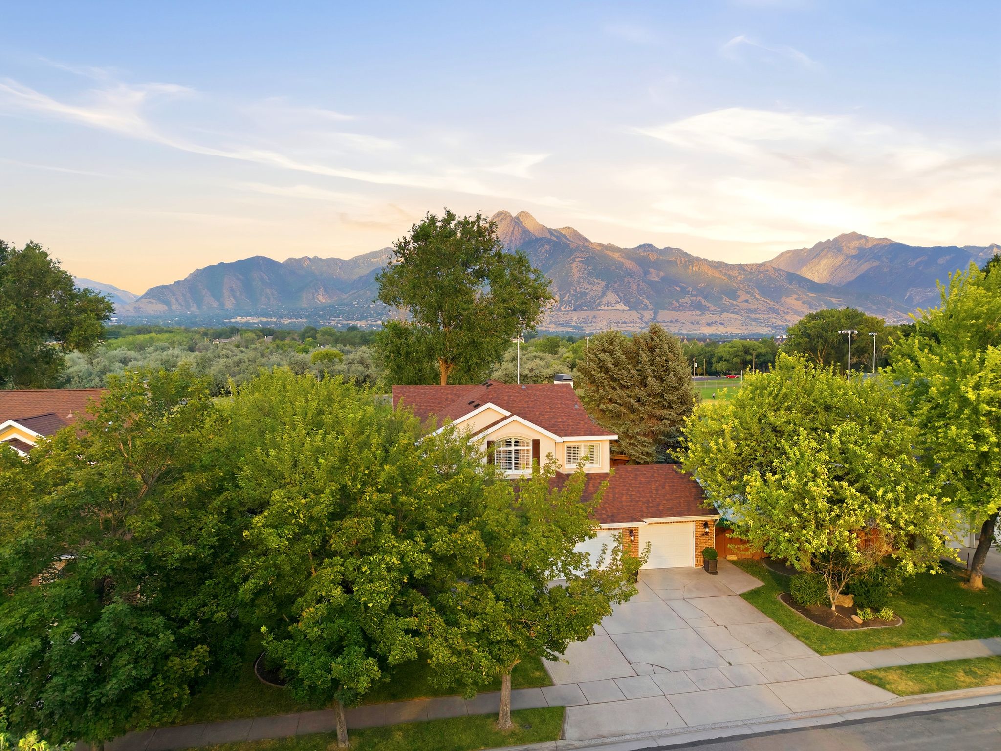 Traditional two-story residence featuring a front-facing garage, mature landscaping, and a concrete driveway