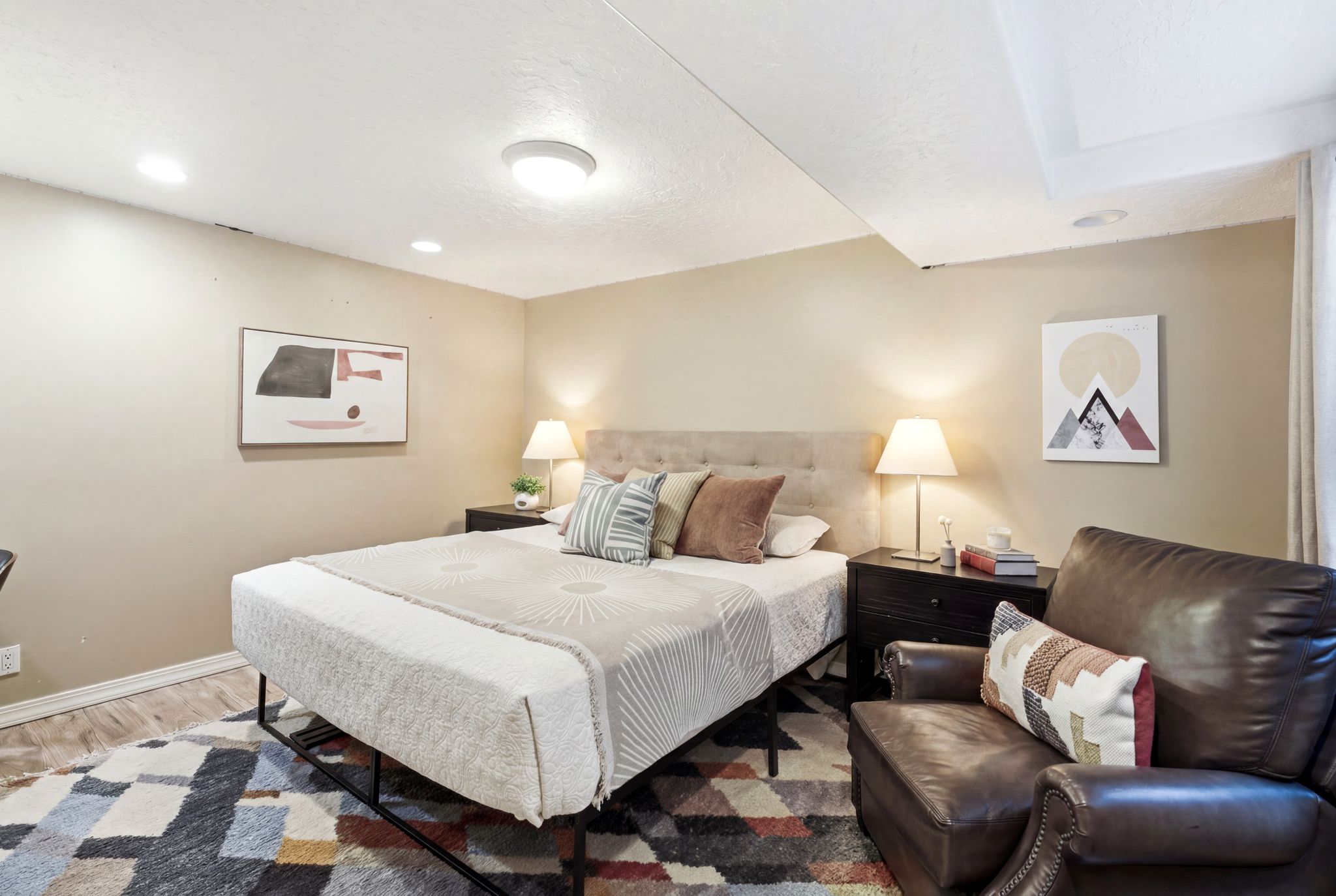 Recessed lighting and a central flush-mount fixture illuminate this space, featuring light-toned walls and wood-finish flooring