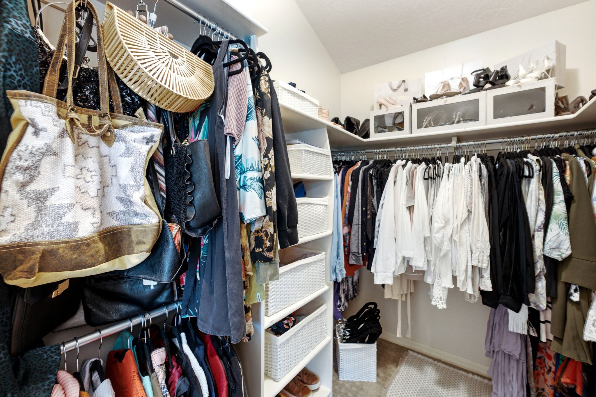 White-painted closet featuring custom shelving, multiple hanging rods, built-in cubbies, and integrated storage units