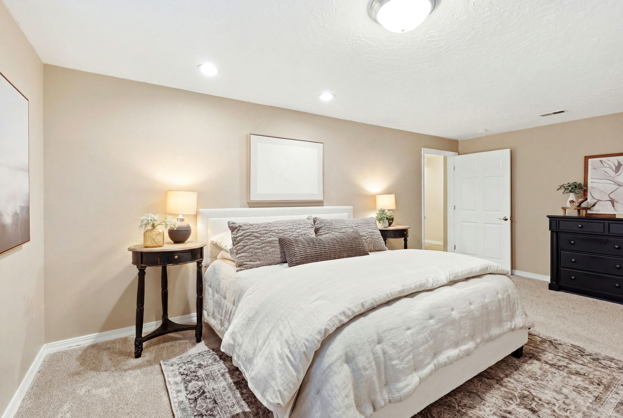 Carpeted room with neutral-toned walls, featuring a white paneled door, a flush-mount ceiling light, and recessed lighting