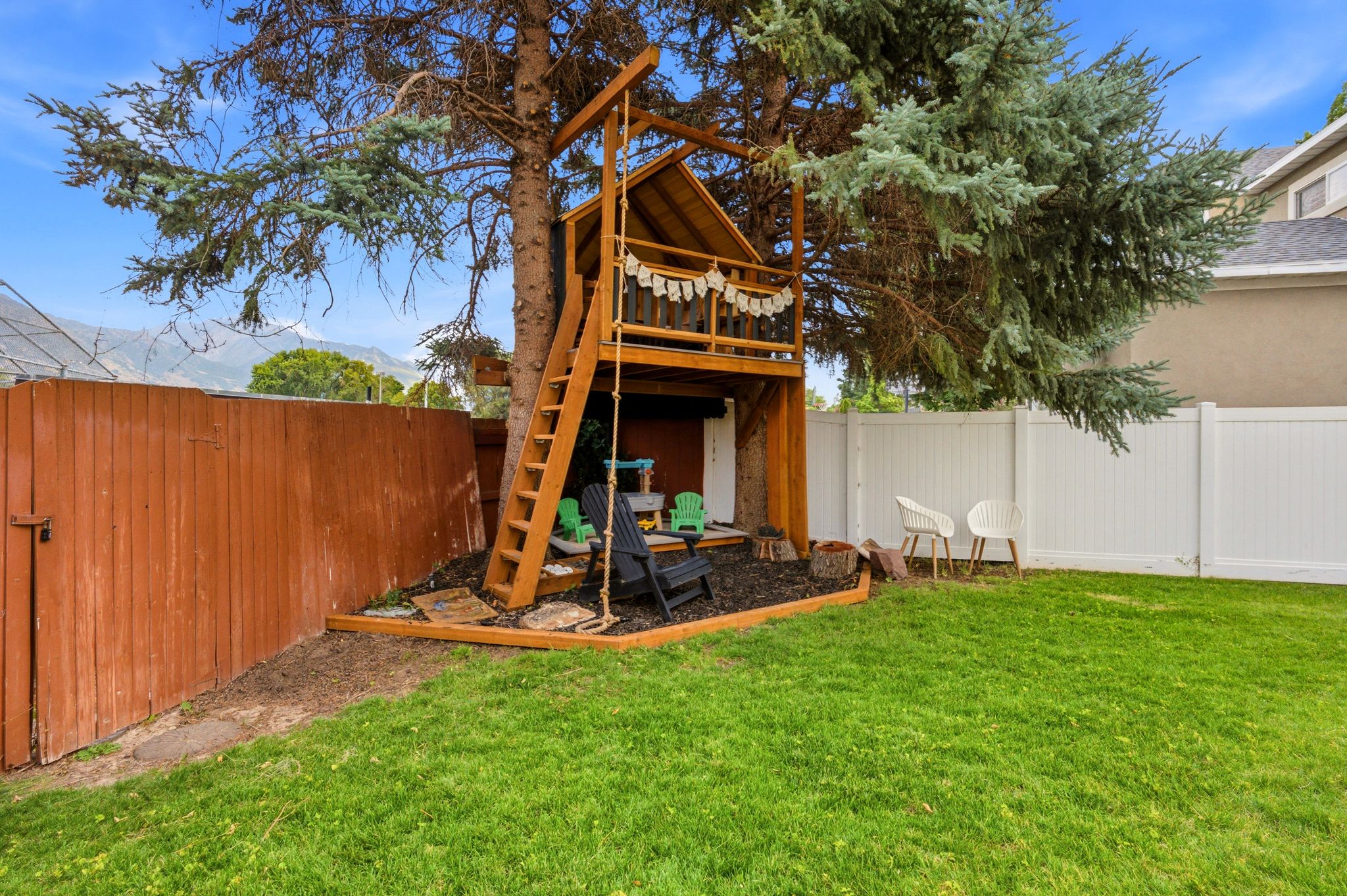 Expansive lawn area featuring a multi-level wooden treehouse structure with a rope swing