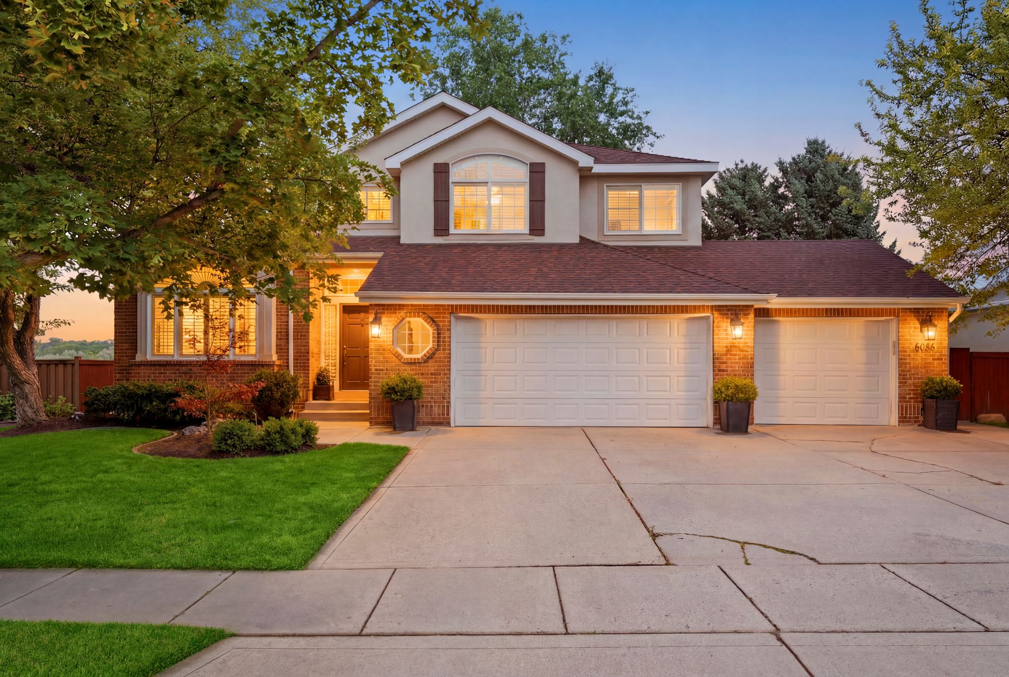 Brick and stucco exterior featuring a bay window, a three-car garage with white paneled doors, and a concrete driveway