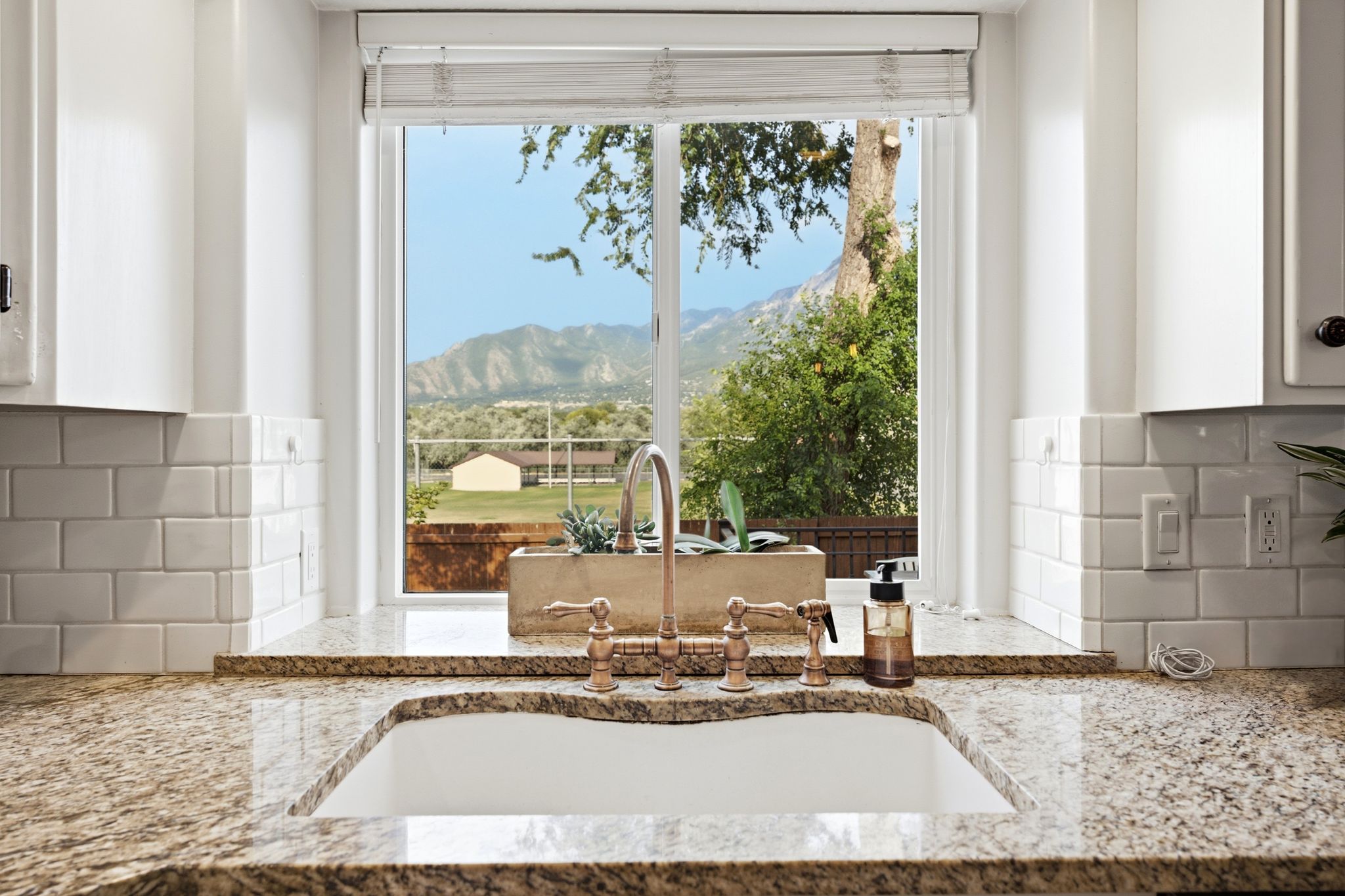 Kitchen sink featuring a granite countertop, undermount sink, and a bronze-finish faucet