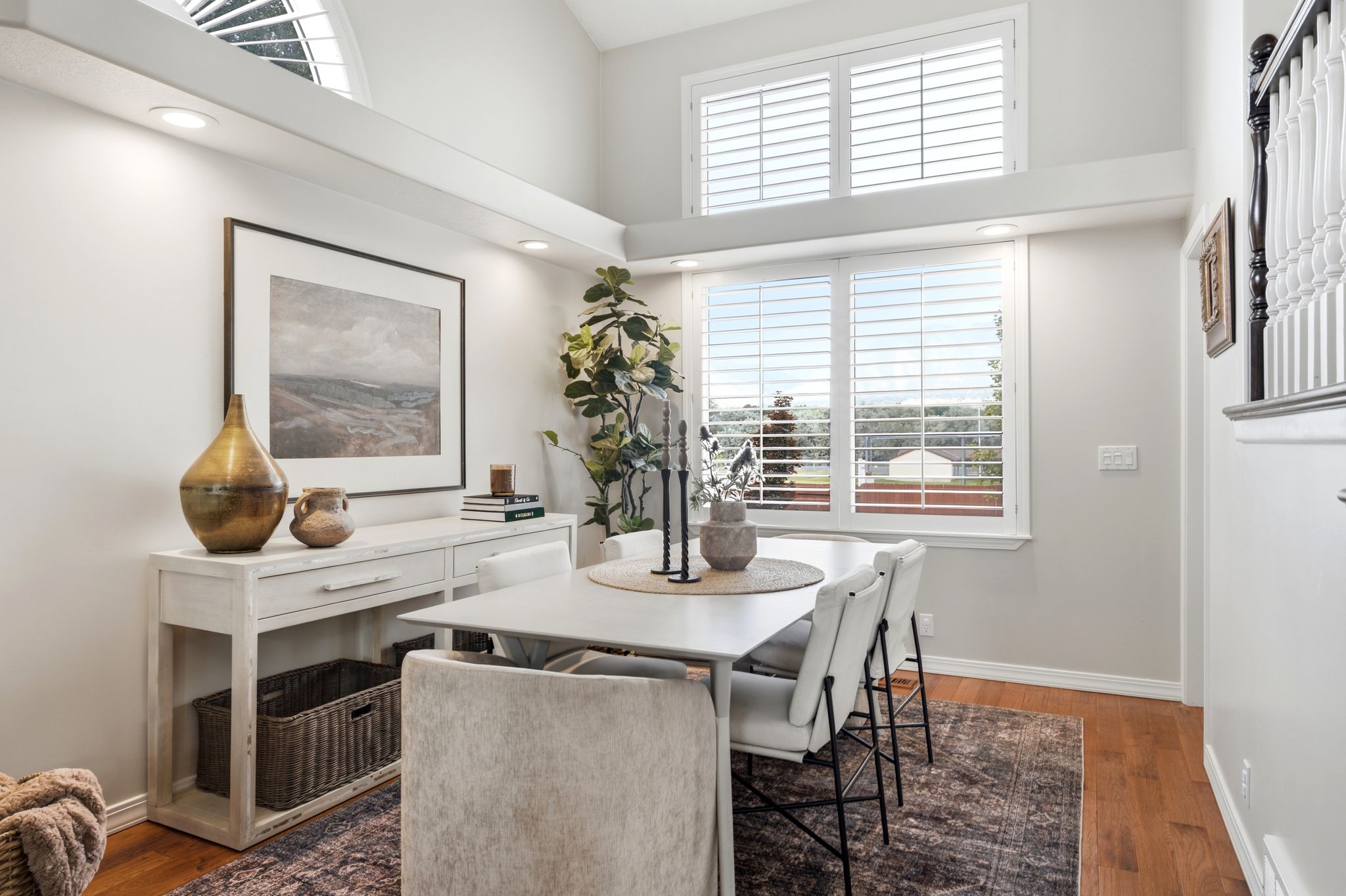 Dining area featuring high ceilings, white plantation shutters, rich wood-finish flooring, and recessed lighting