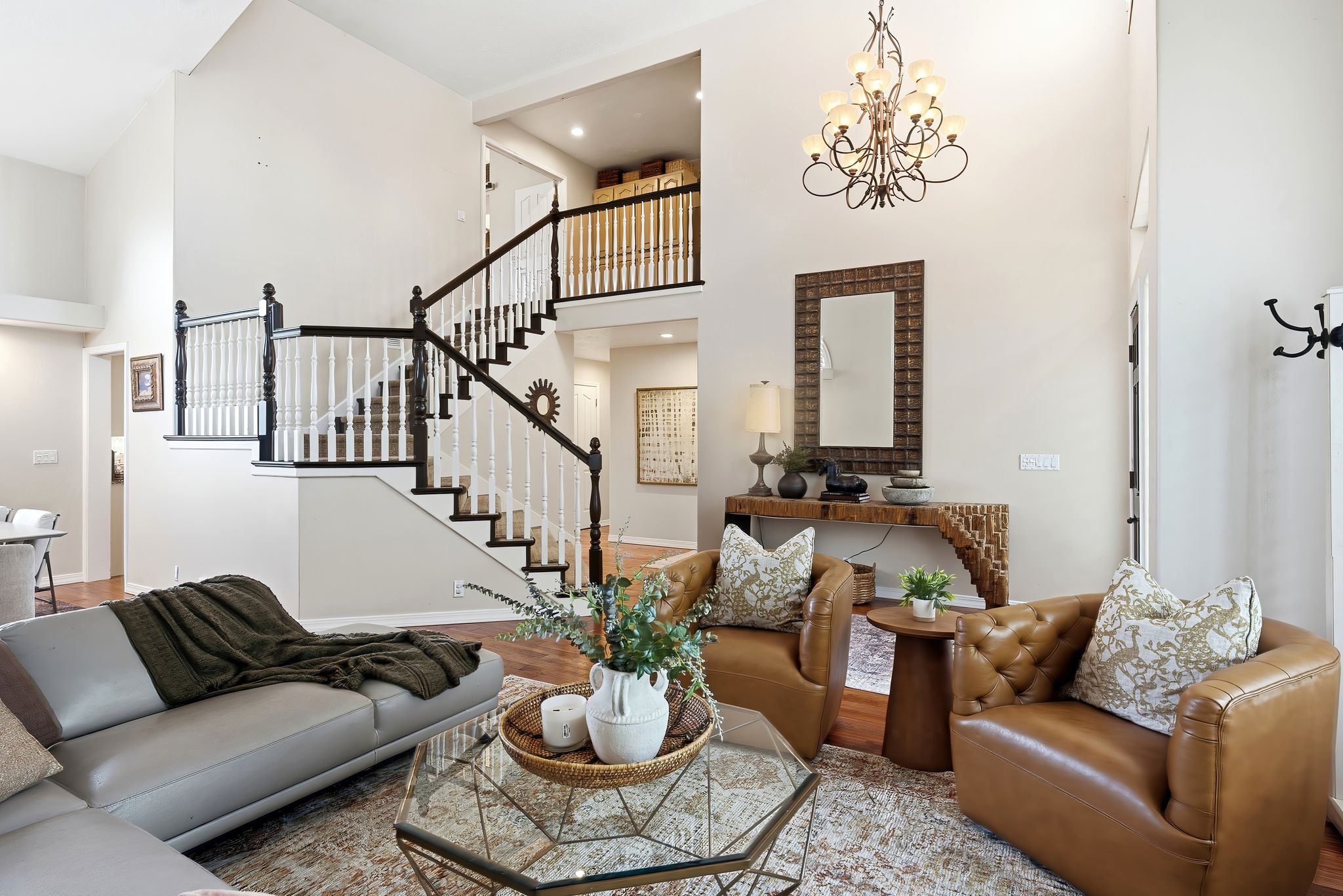 Soaring ceilings with an ornate chandelier and hardwood-finish flooring