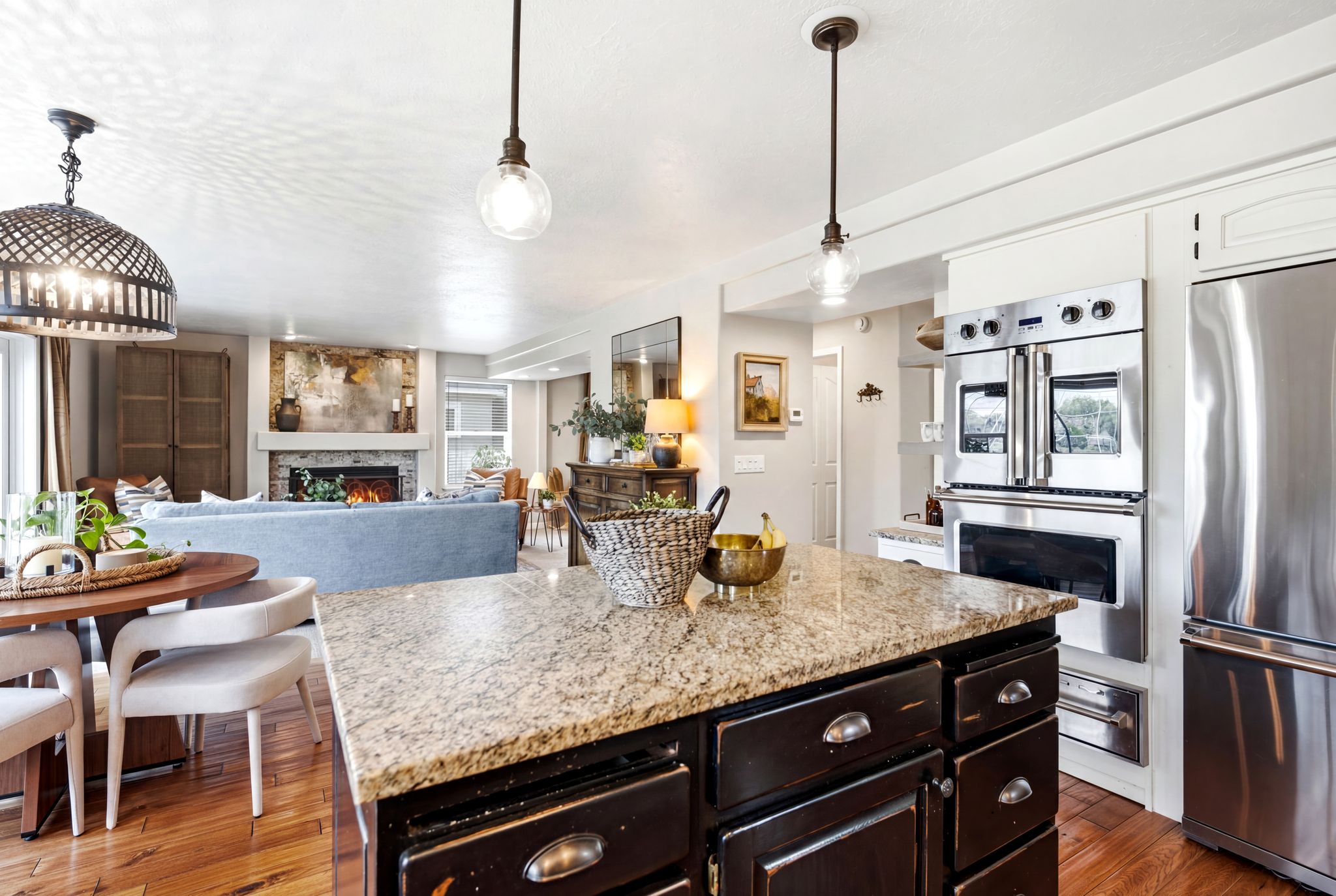 Kitchen island with granite countertop, dark wood cabinetry, and pendant lighting