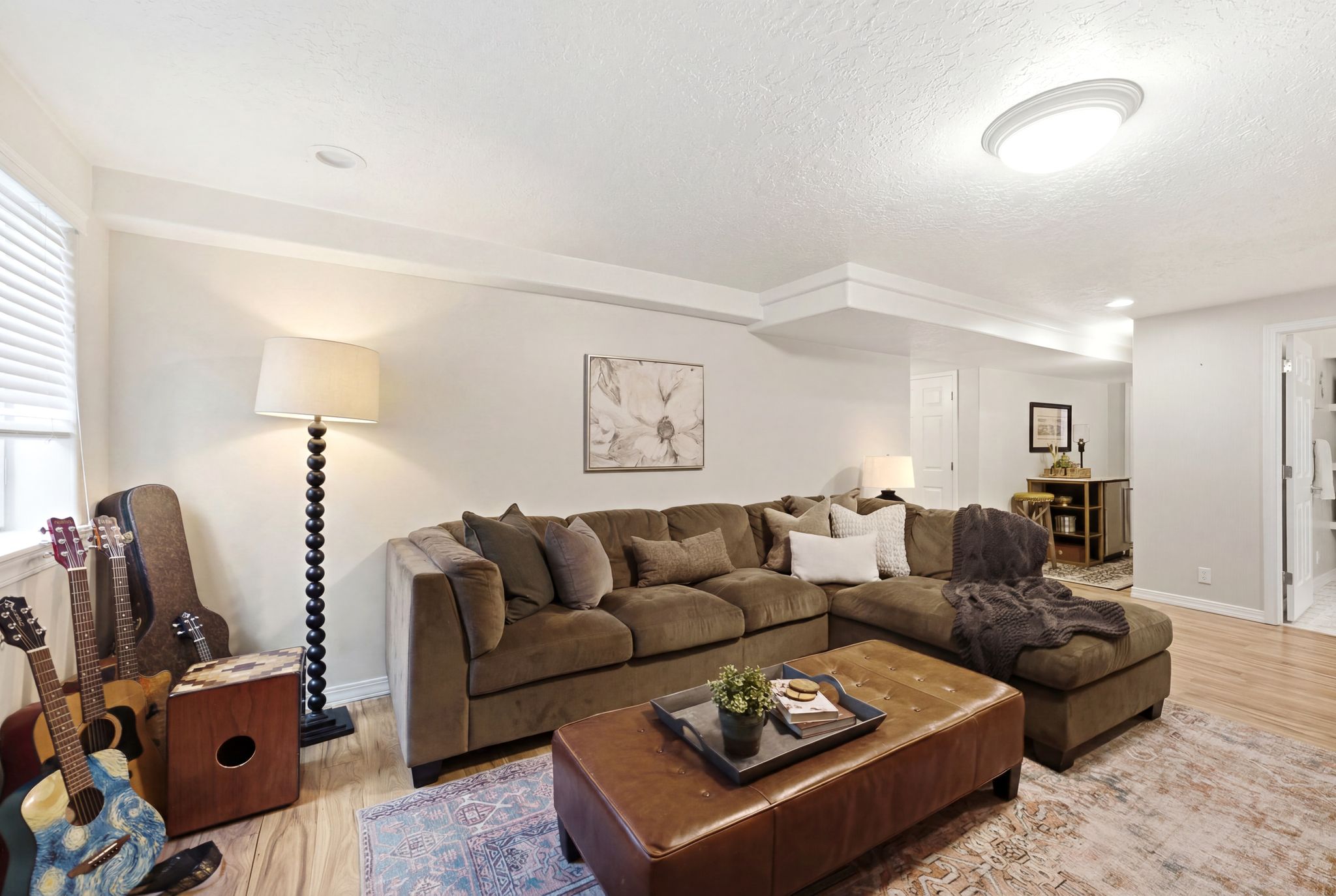 Spacious living area featuring wood-finish flooring, recessed lighting, and a window with blinds