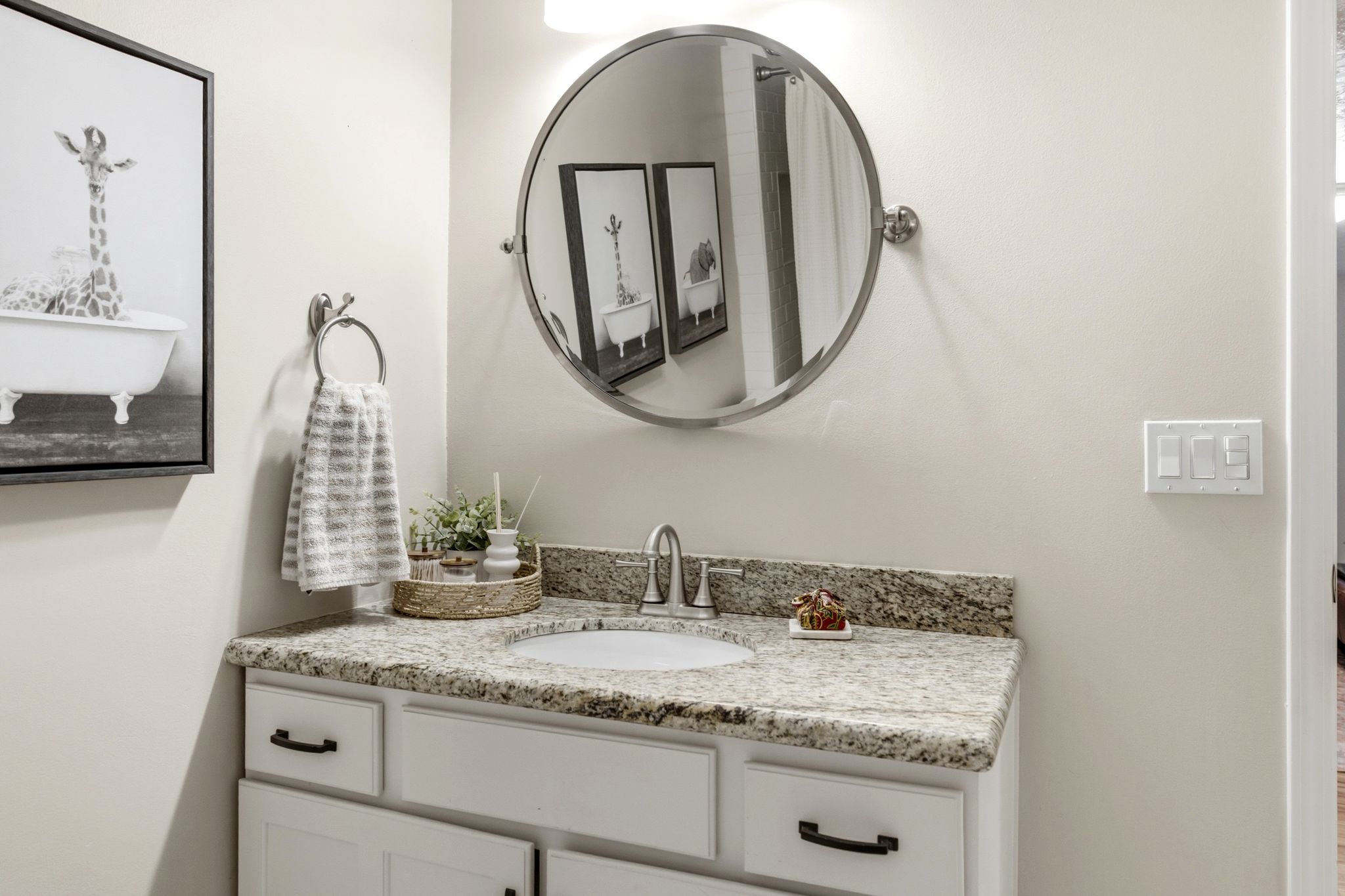 Bathroom vanity with a light granite countertop, undermount sink, and brushed nickel faucet