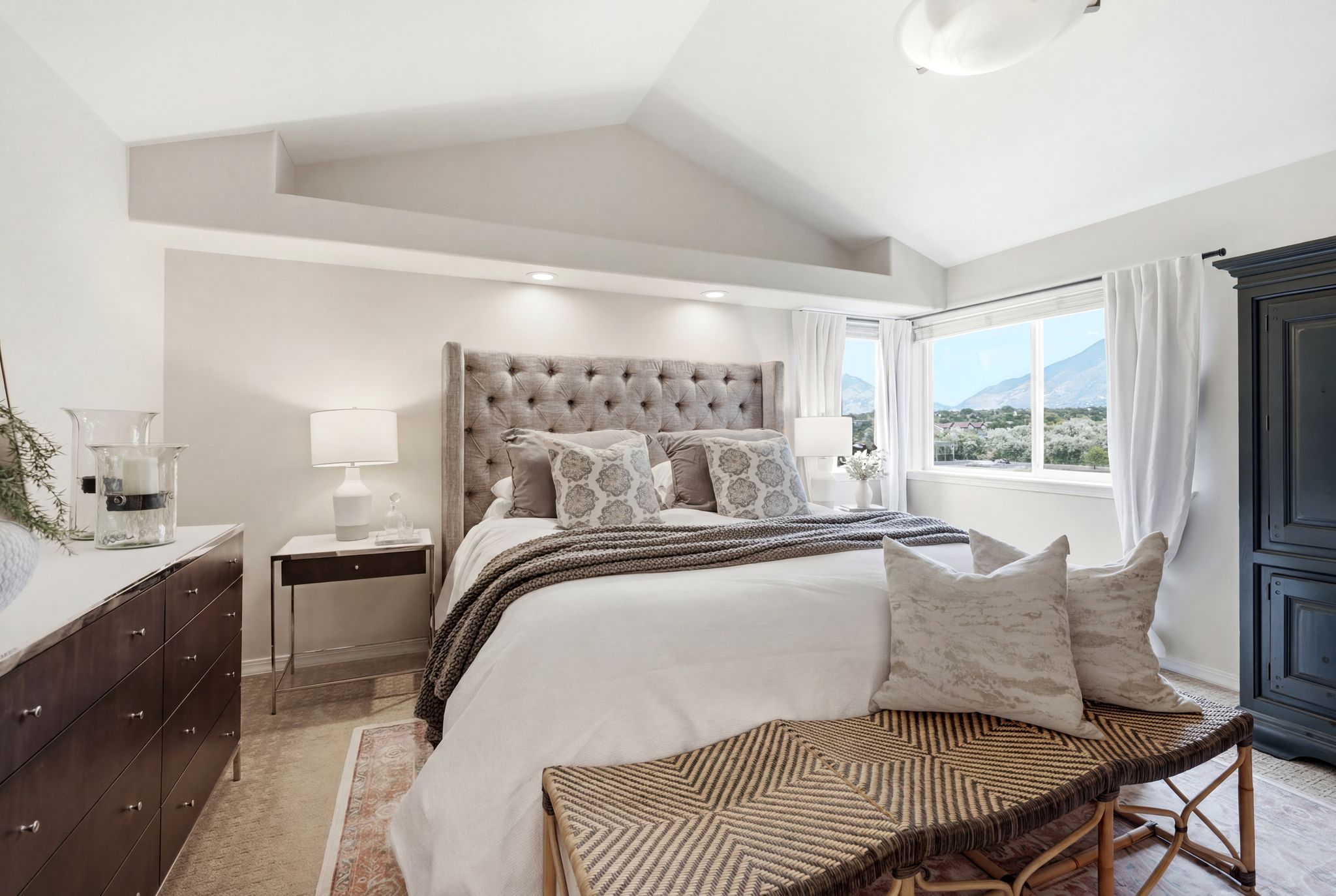 Vaulted ceiling bedroom with recessed lighting and a large window offering mountain scenery