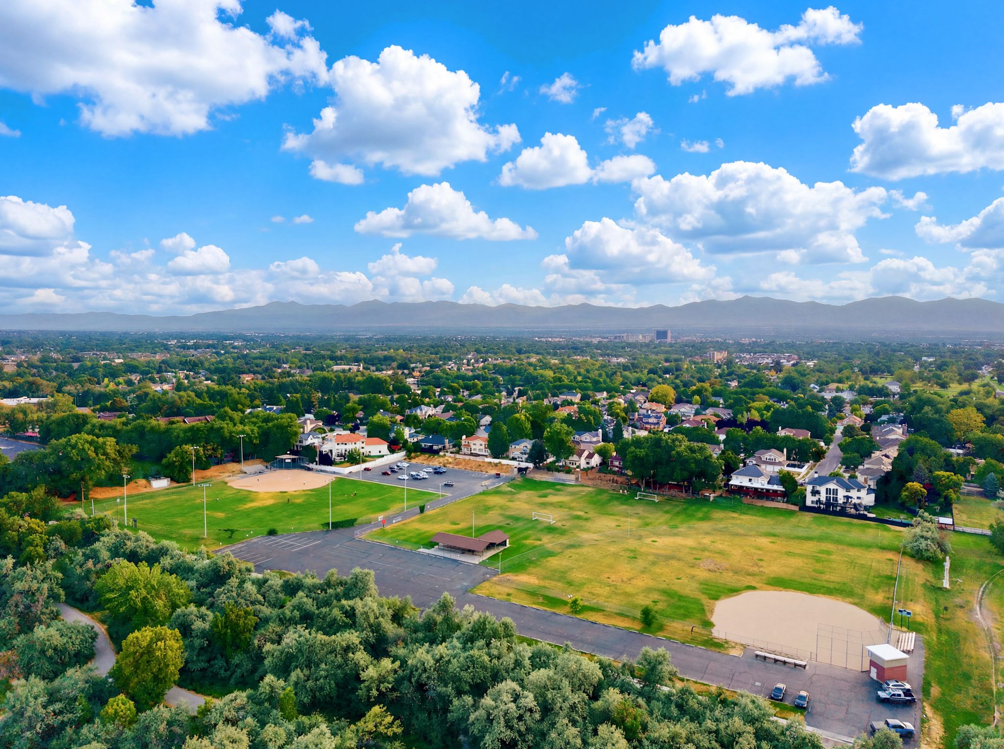 Expansive aerial showcasing a residential area with lush tree cover and distant mountain ranges