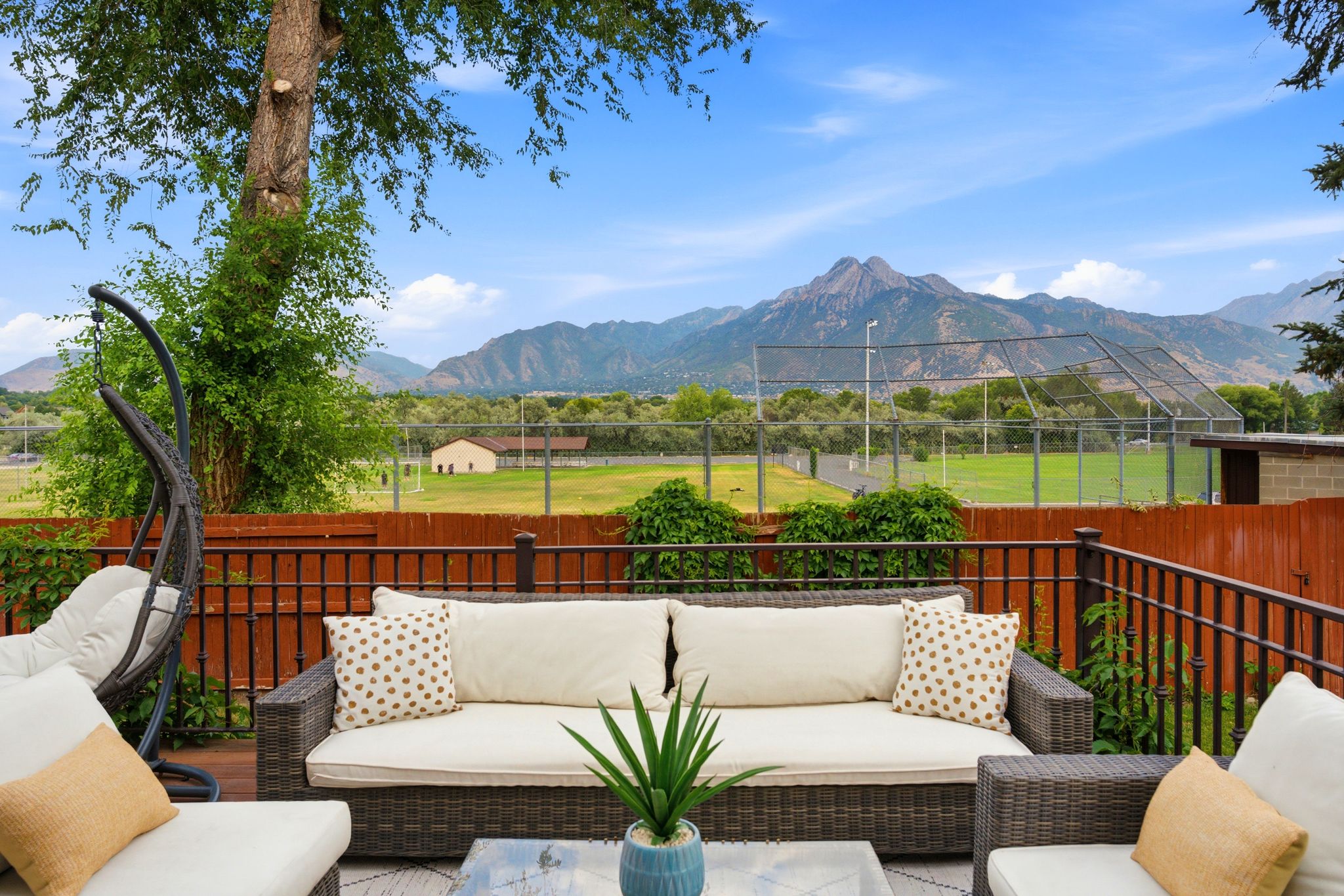 Outdoor deck featuring a wood surface, black metal railing, and a privacy fence