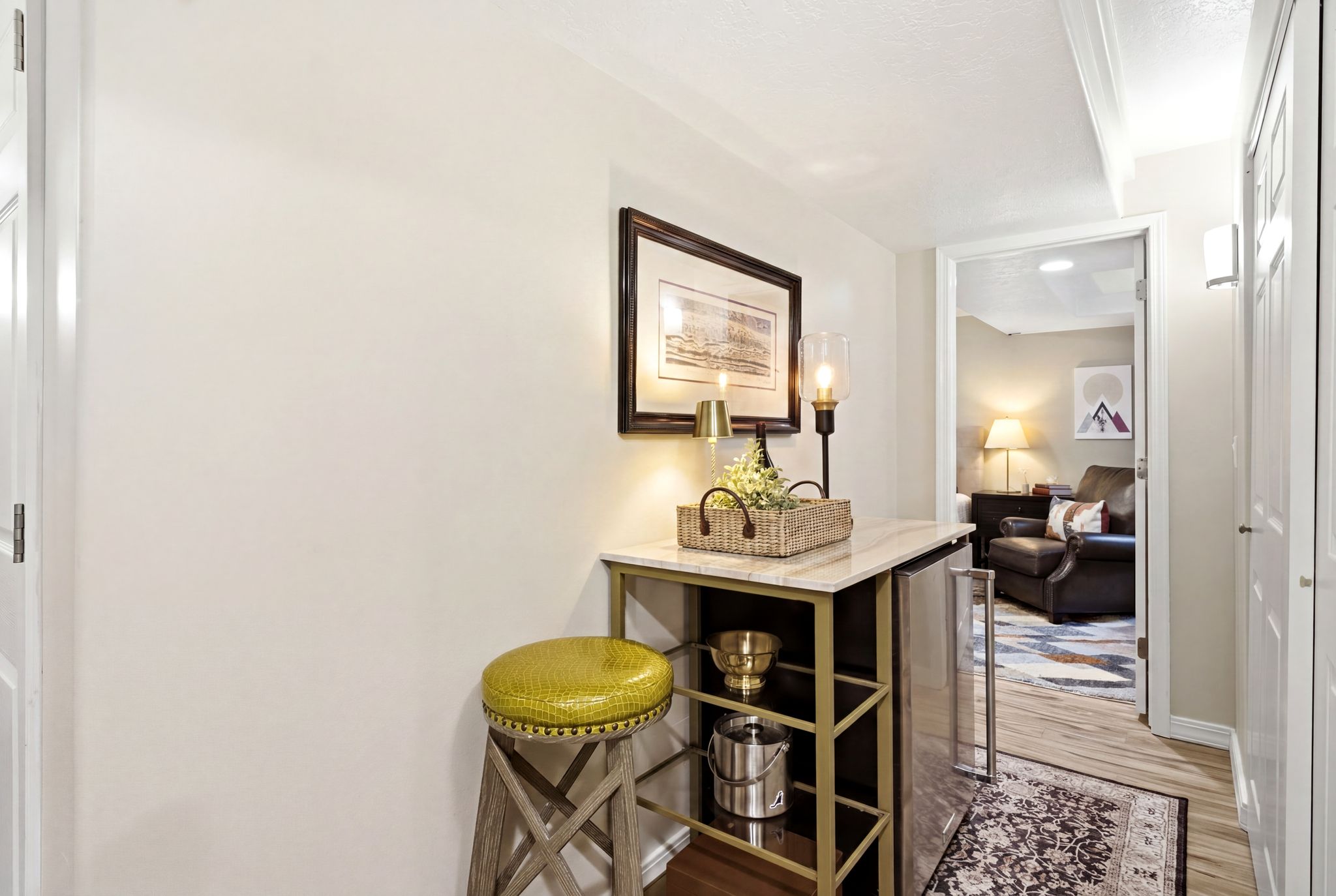 Built-in beverage bar featuring a marble-finish countertop, gold-tone shelving, and an integrated stainless steel mini-refrigerator
