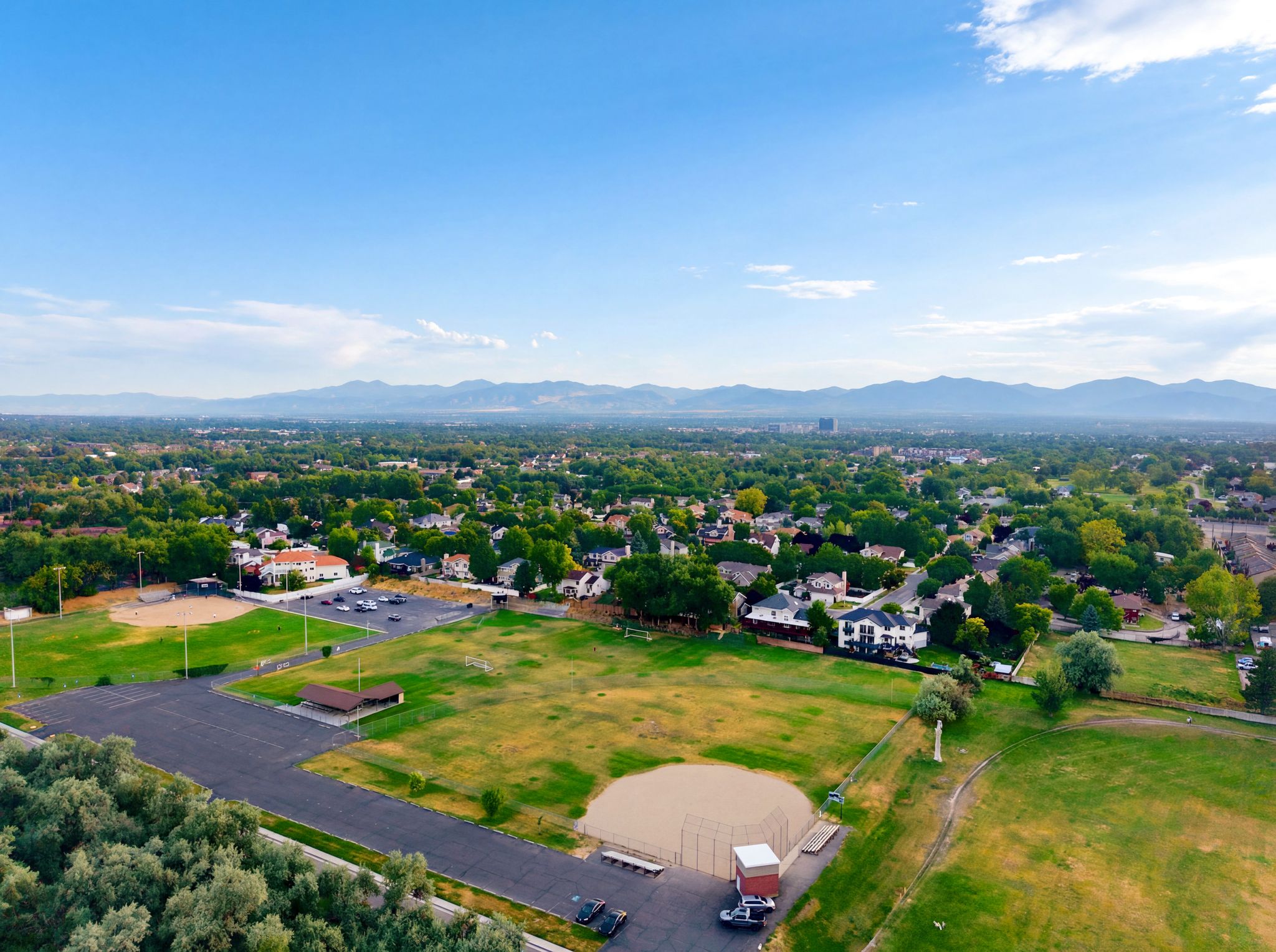 Expansive aerial panorama showcasing a residential area with varied housing styles and abundant mature trees