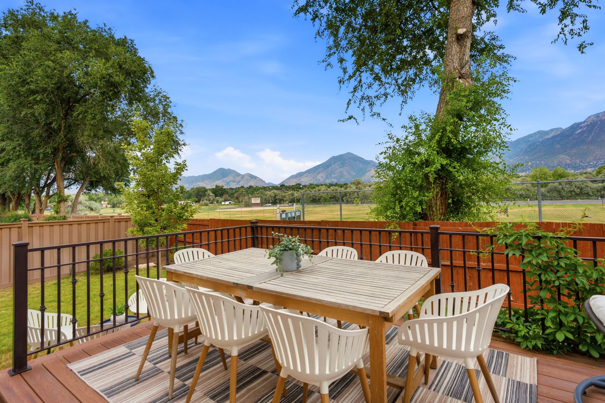 Expansive wooden deck featuring dark-stained wood-finish flooring and a black metal railing