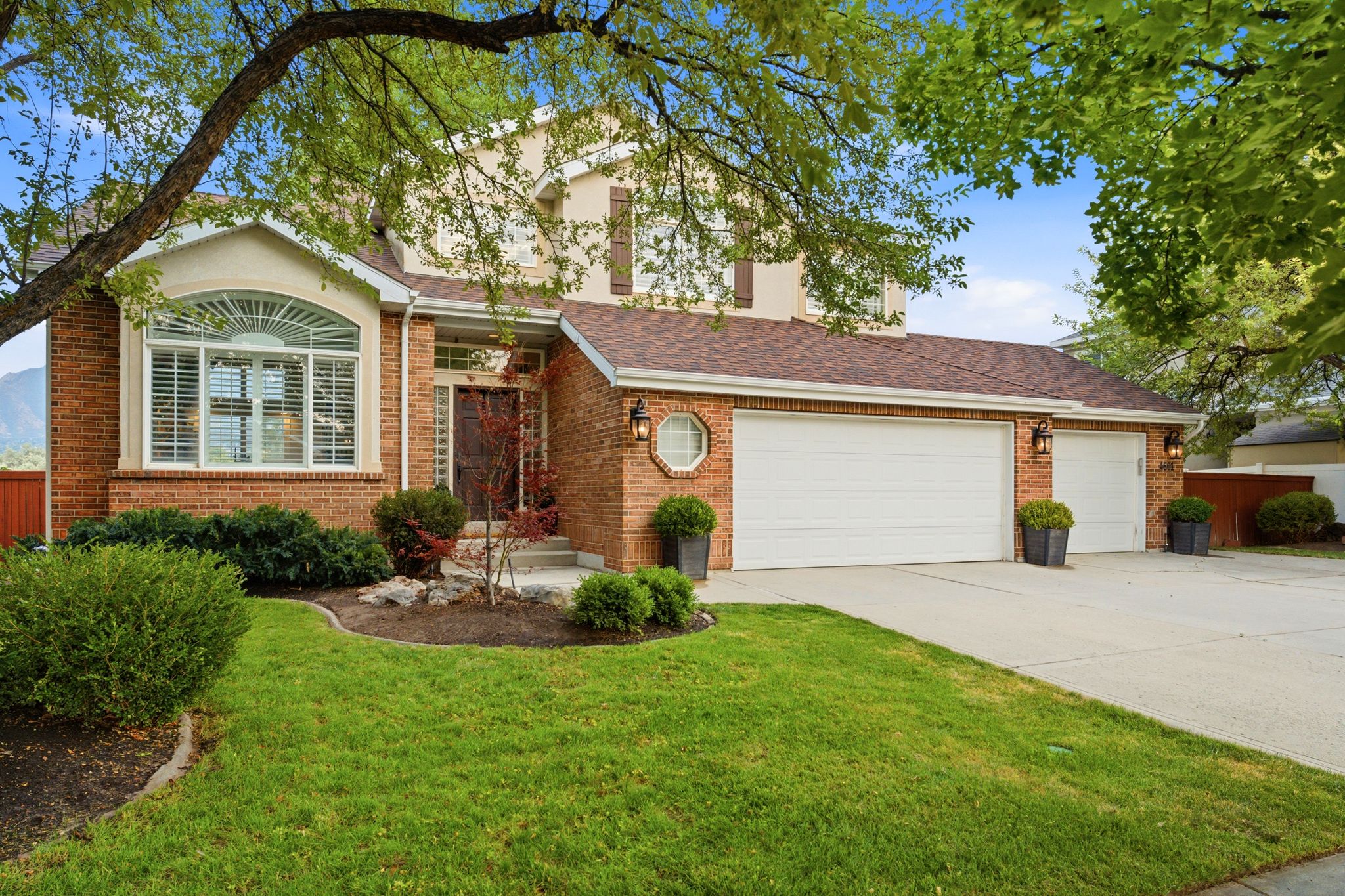Brick exterior with a prominent arched window, a two-car garage, and a single-car garage