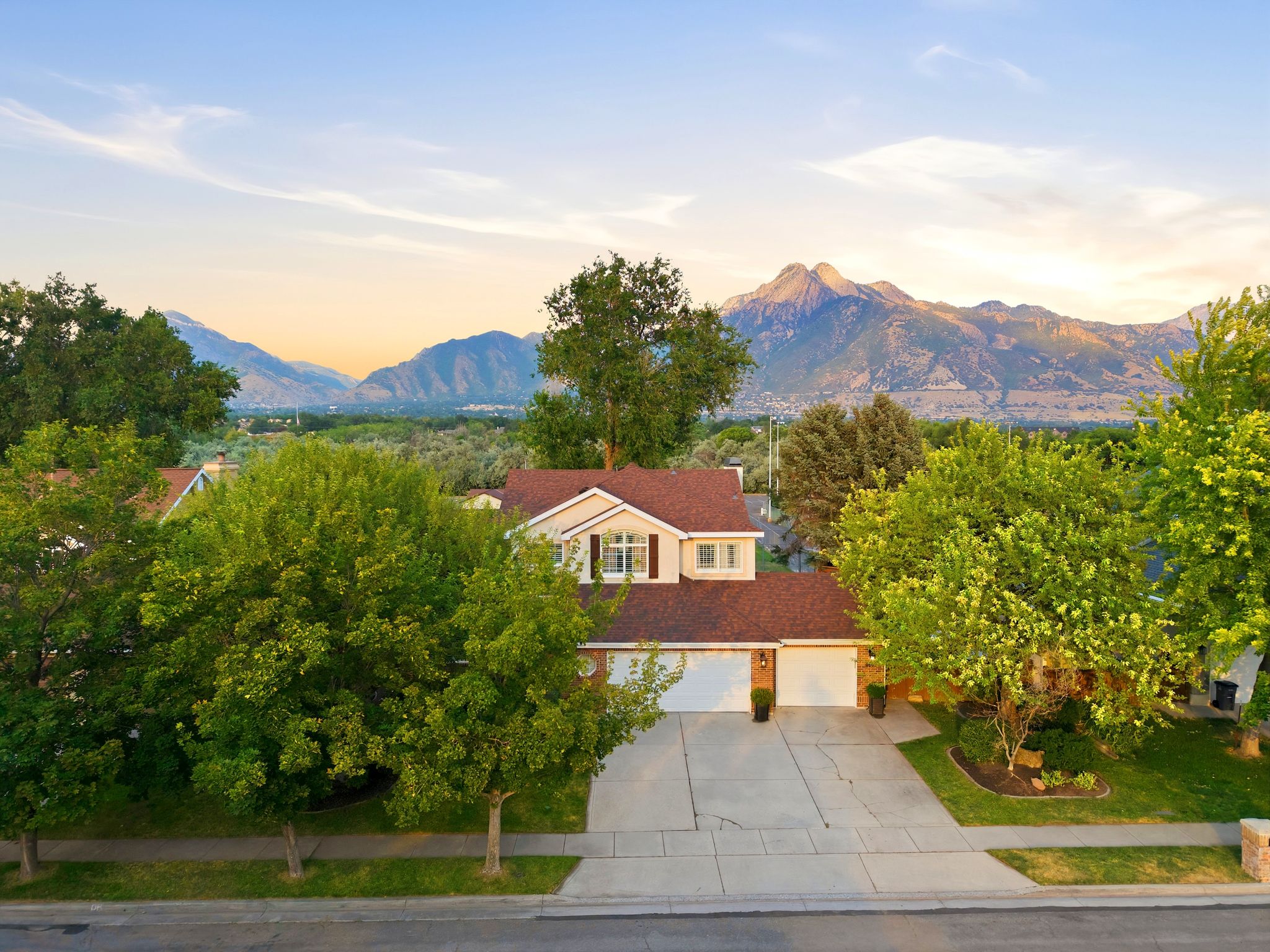 Two-story residence featuring a two-car garage, concrete driveway, and mature landscaping