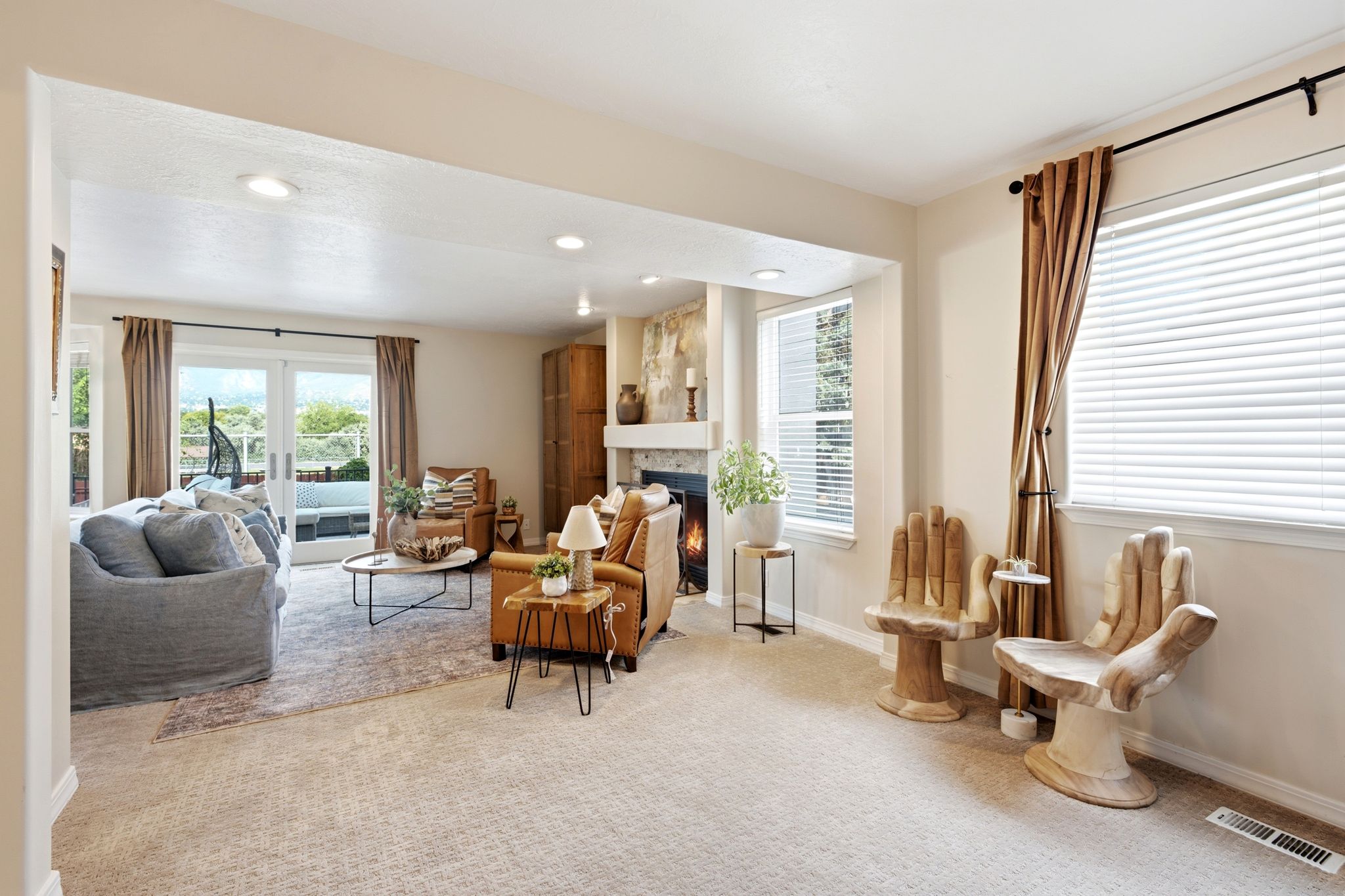 Spacious living area featuring light-colored carpeting, recessed lighting, and a stone-faced fireplace