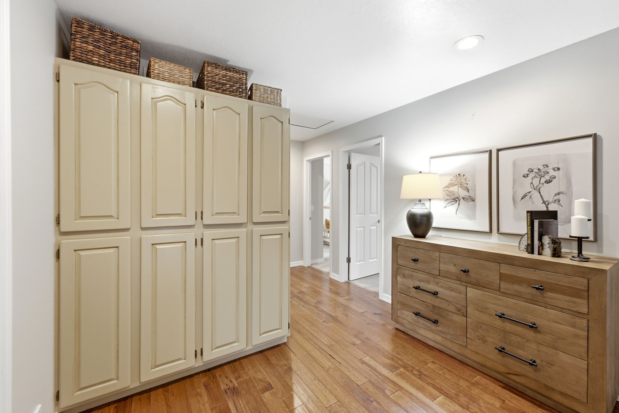 Hallway featuring built-in cabinetry, wood-finish flooring, recessed lighting, and a white paneled door