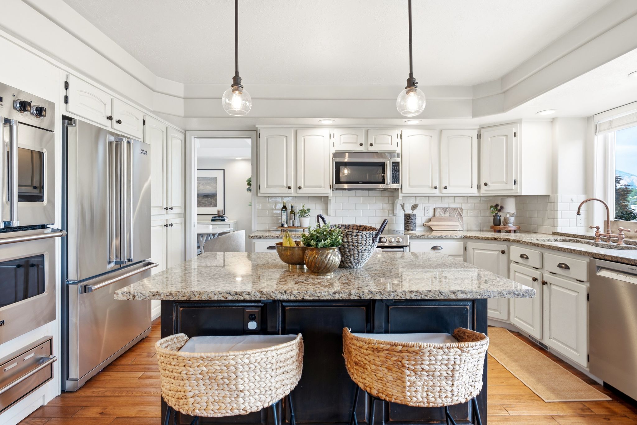 Kitchen featuring a central island with a granite countertop, white cabinetry, stainless steel appliances, and wood-finish flooring