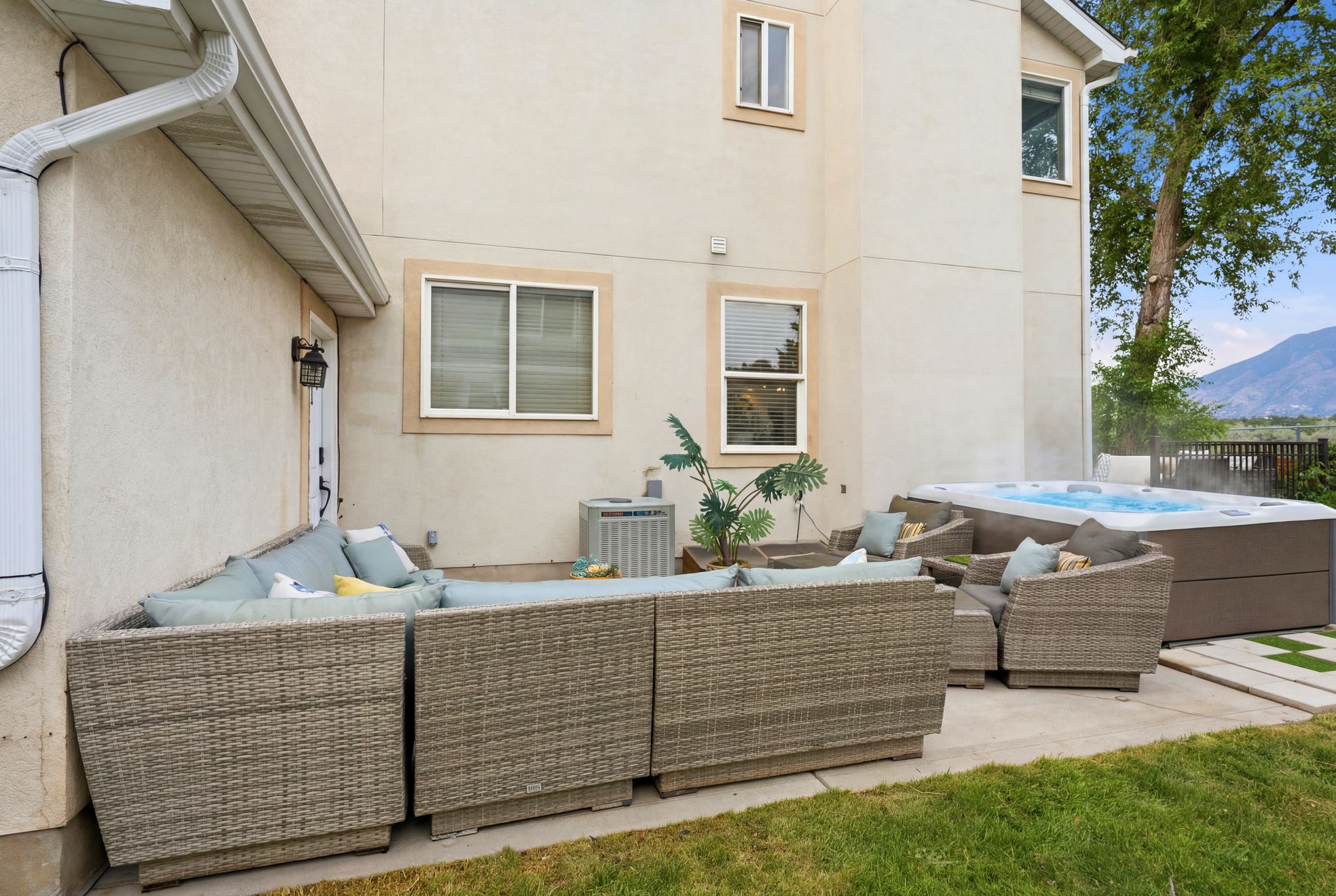 Spacious concrete patio featuring a built-in spa, stucco exterior, and mountain backdrop