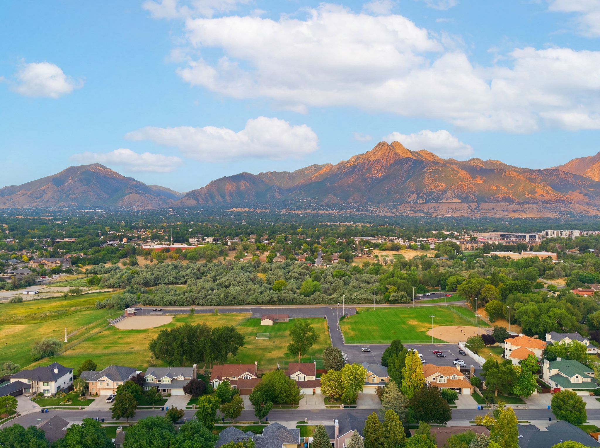 Expansive neighborhood showcasing a variety of residential properties, recreational green spaces, and mountain scenery