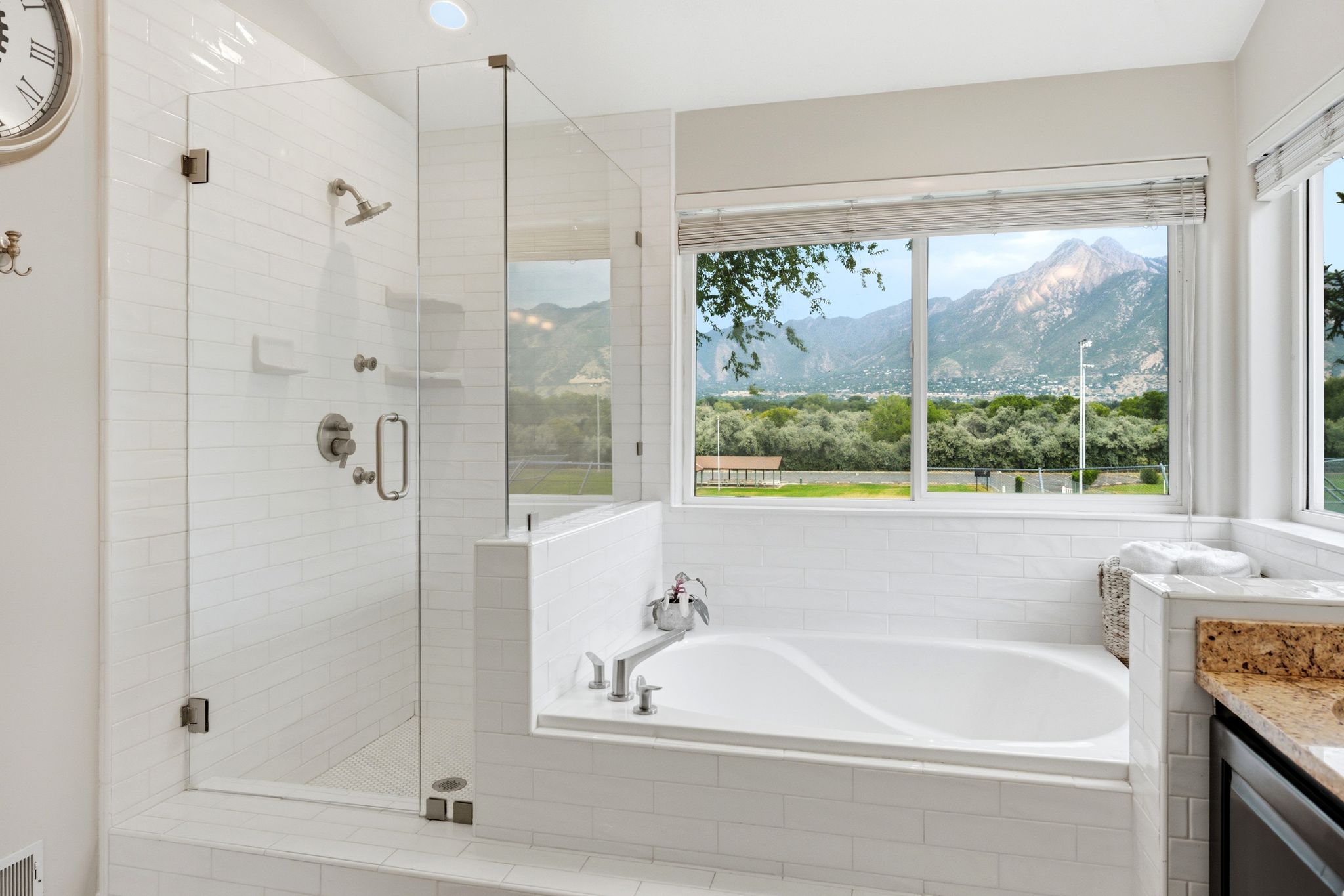 Spacious bathroom featuring a built-in soaking tub, a separate glass-enclosed shower, and a large window overlooking a mountainous landscape