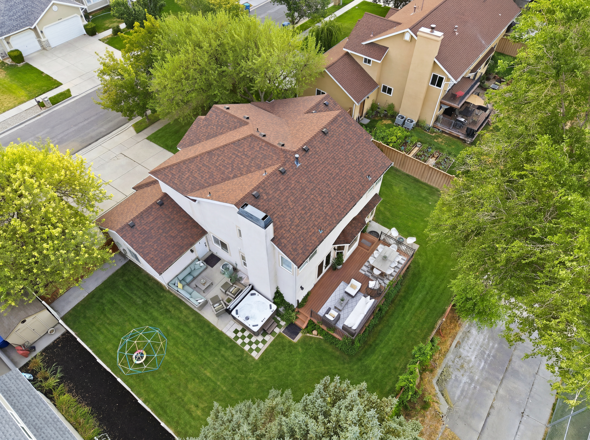 Expansive backyard featuring a large green lawn, two distinct patio areas, and mature trees