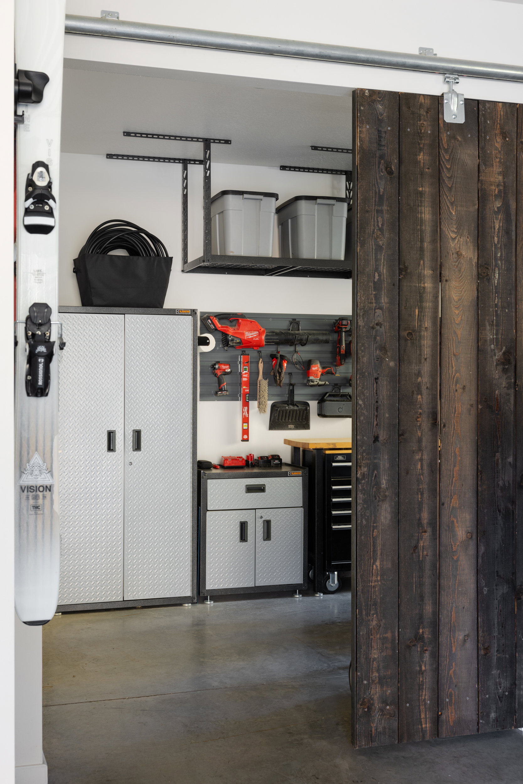 Garage featuring a barn door entry, concrete flooring, overhead storage racks, metal cabinetry, and a wall-mounted tool organization system