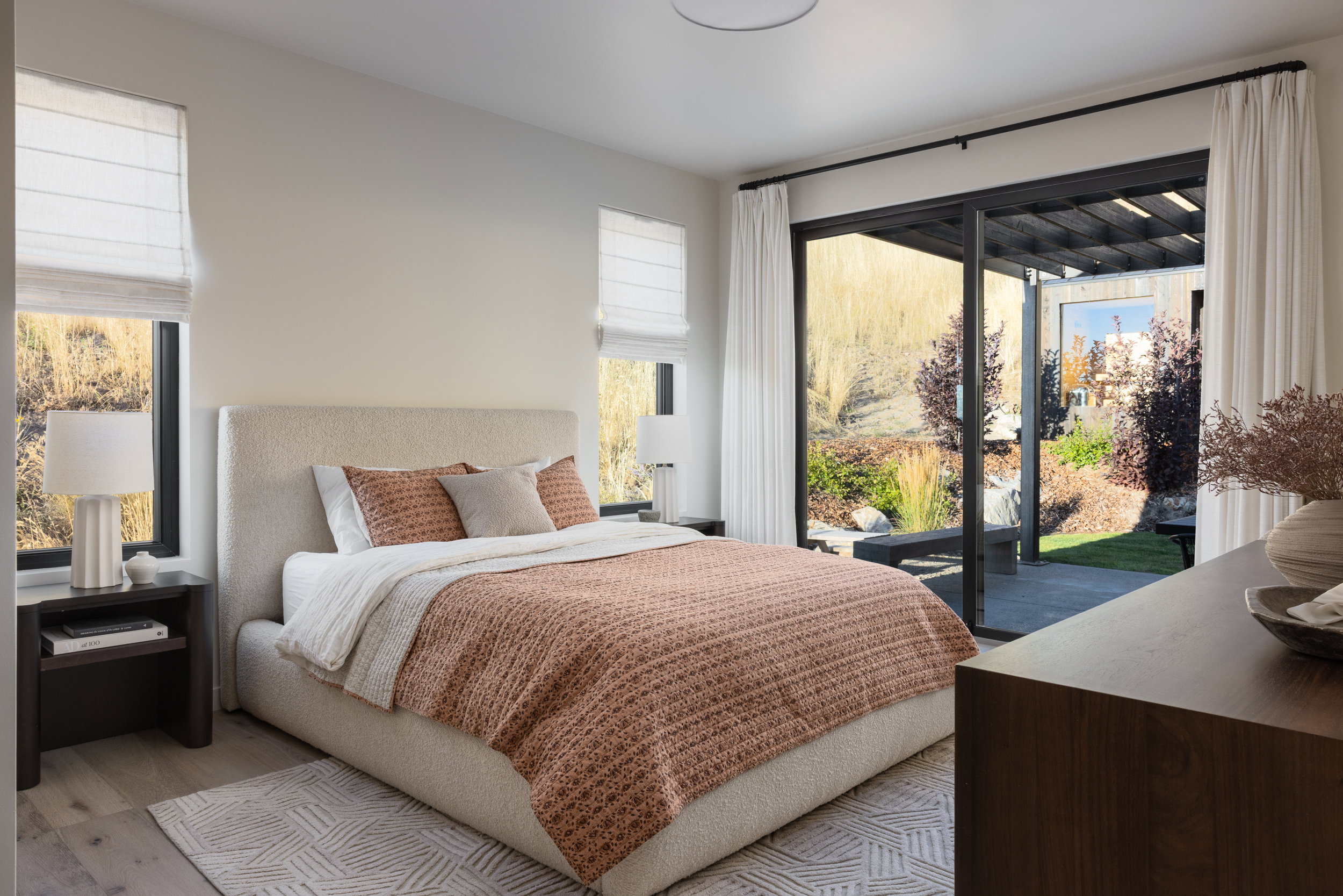Bright room featuring a full-light sliding door to the patio, wood-finish flooring, two large windows with roman shades, and a ceiling-mounted light fixture