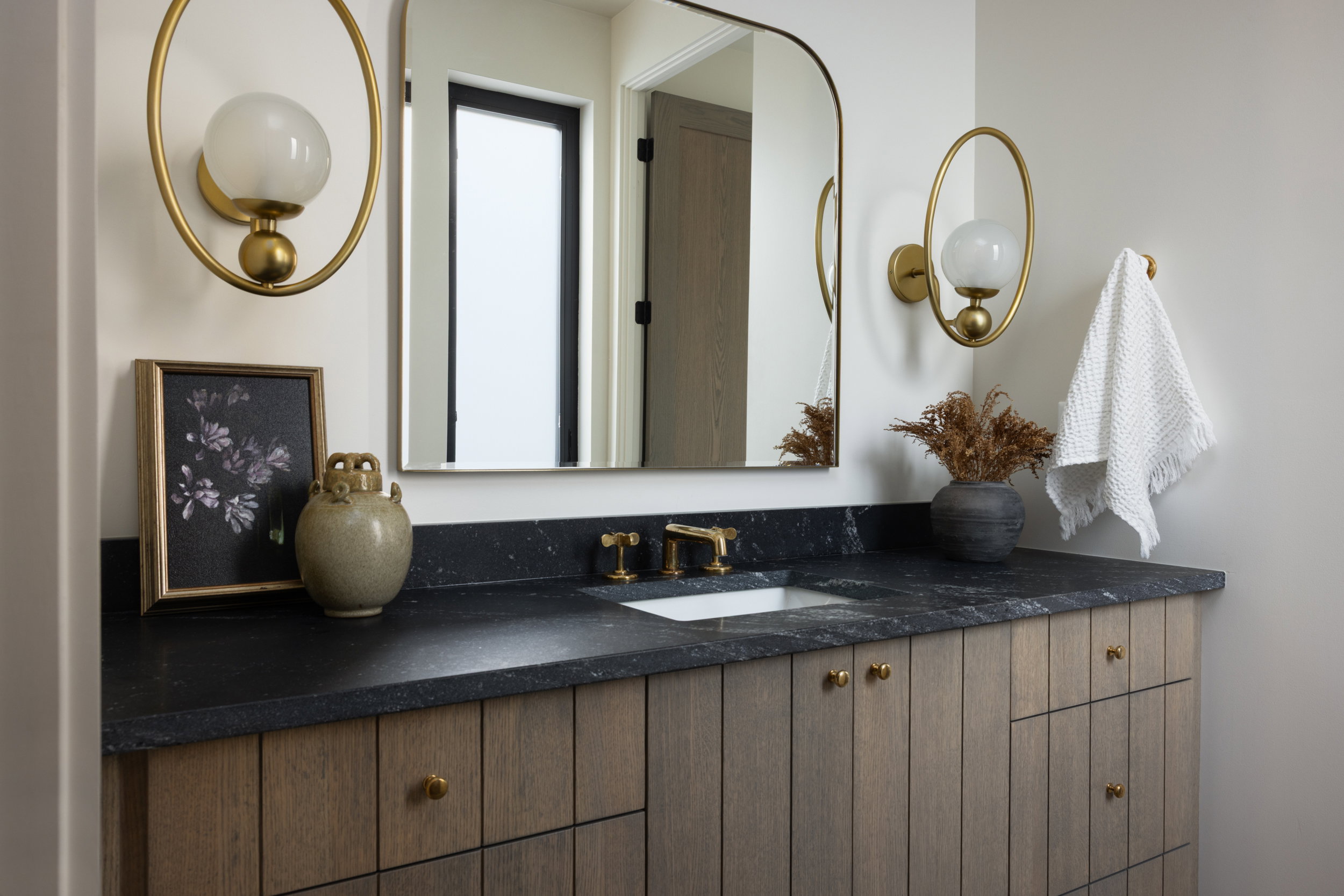 Bathroom vanity featuring a dark countertop, an undermount sink, and a gold-toned faucet