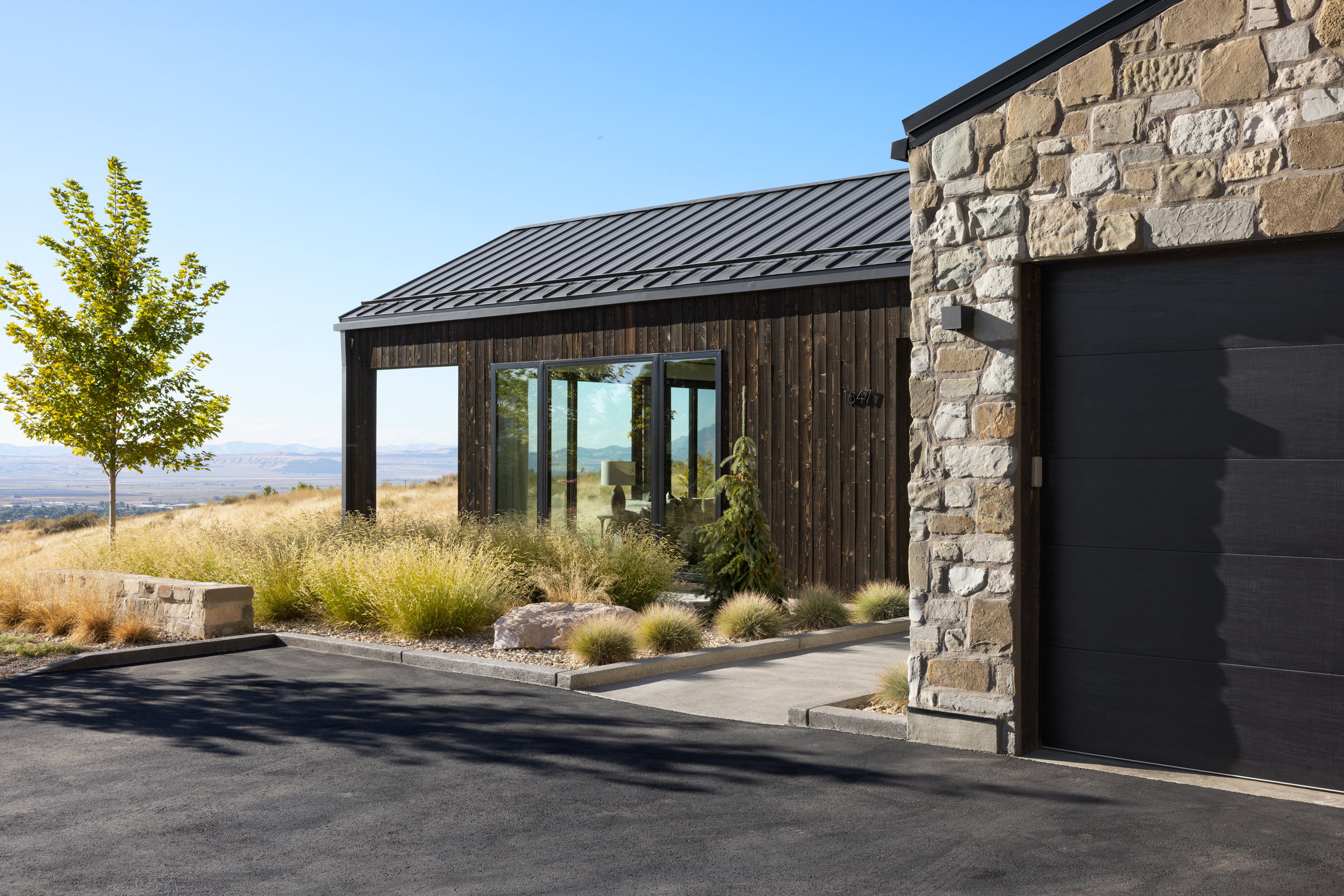 Contemporary exterior featuring a metal roof, dark wood siding, and stone accents