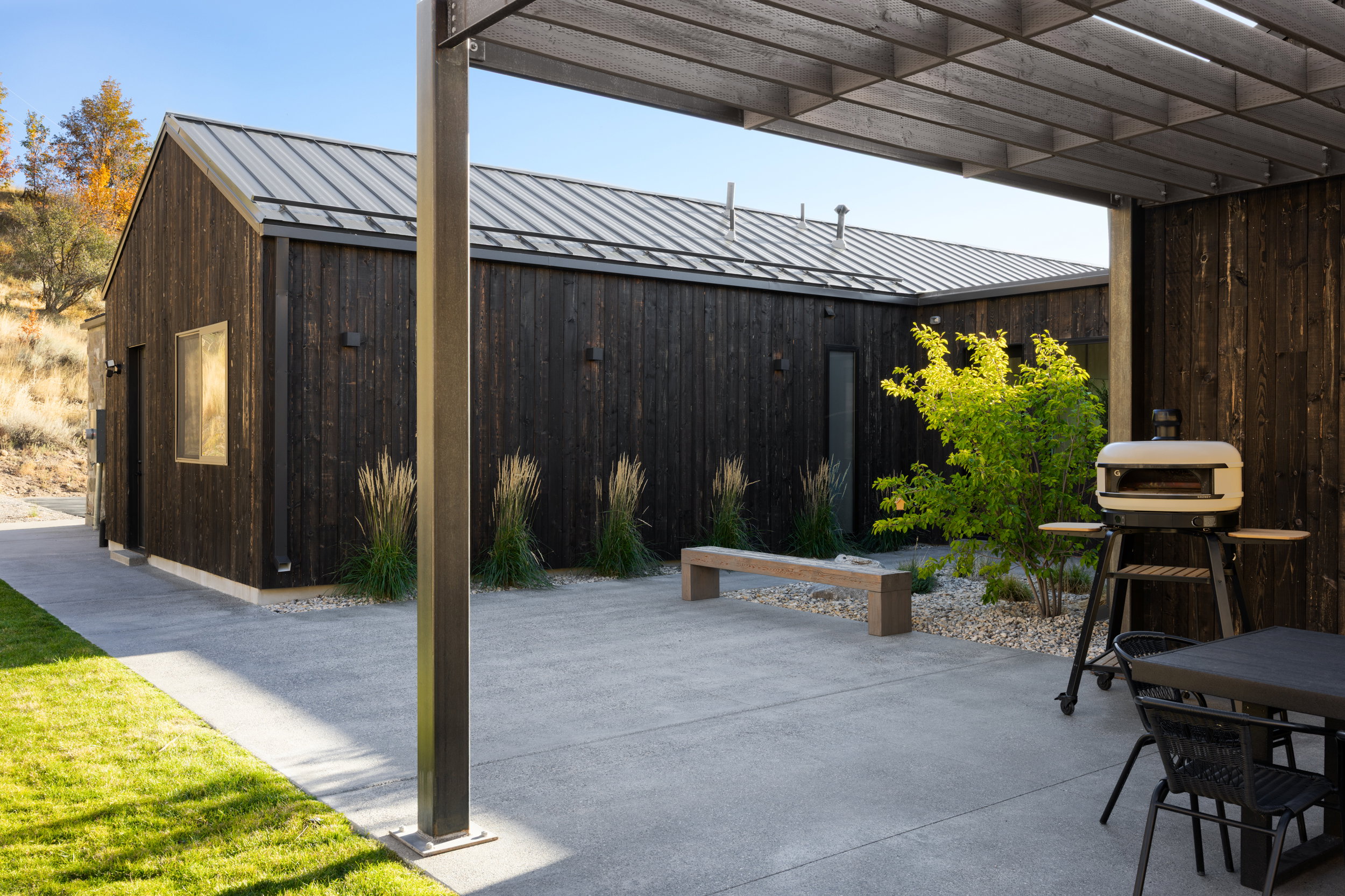 Modern exterior featuring dark wood siding, a metal roof, and a concrete patio