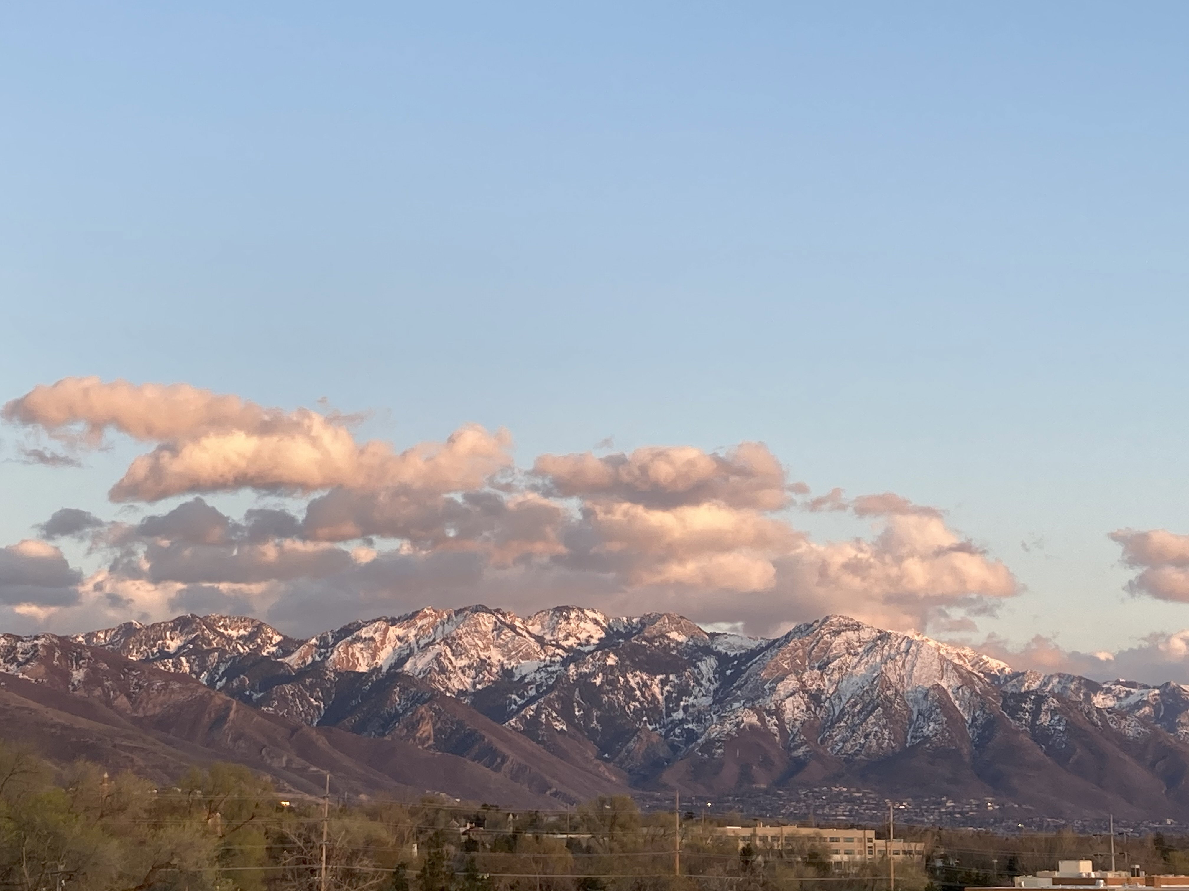 Mountain range featuring snow-capped peaks under a light blue sky with scattered clouds