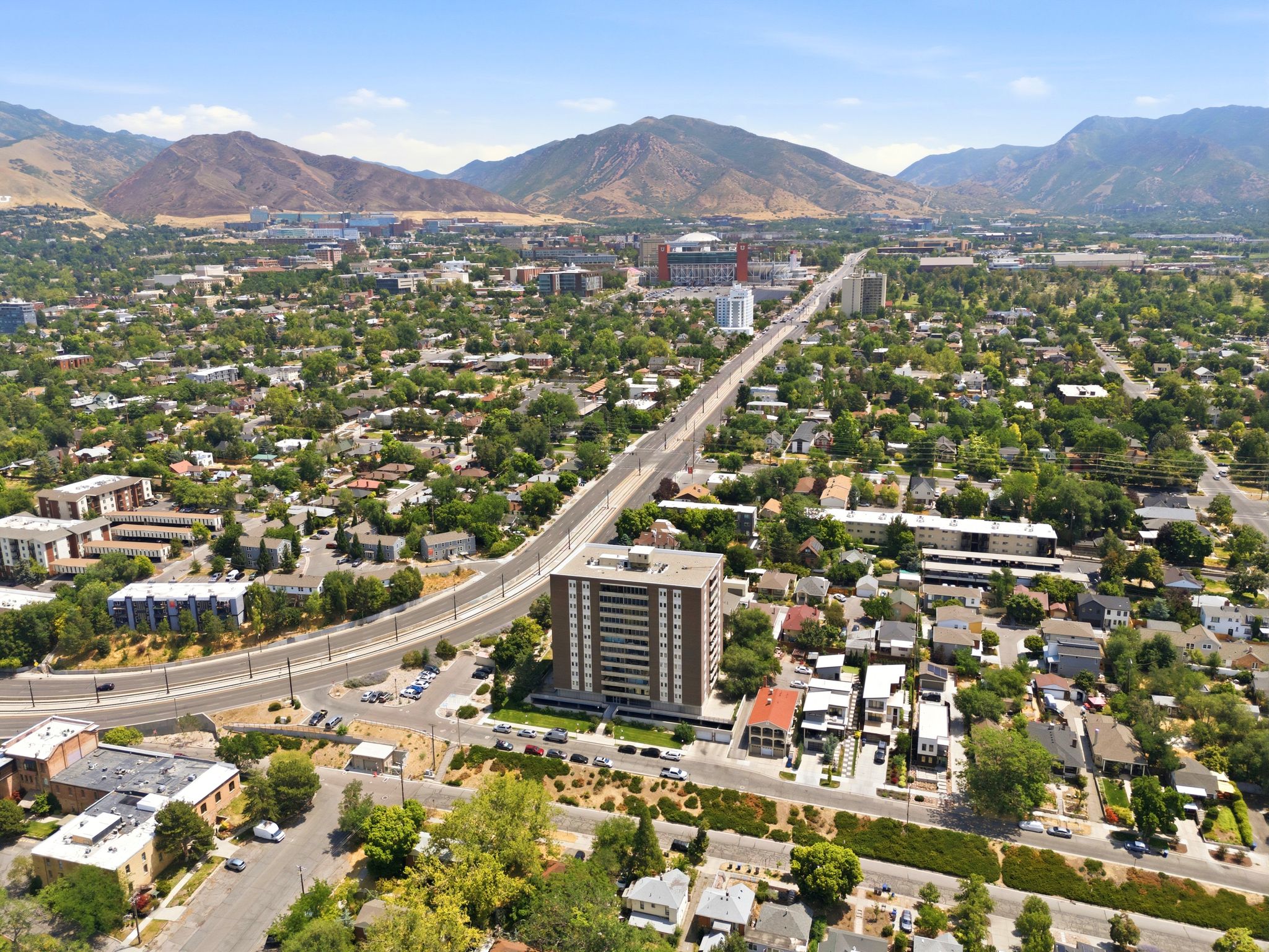 Elevated urban setting with a prominent high-rise building, surrounded by a residential area with mature trees and a substantial roadway