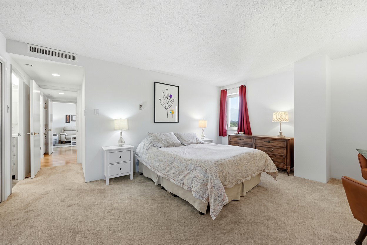 Carpeted bedroom with a window, white walls, and a hallway entry