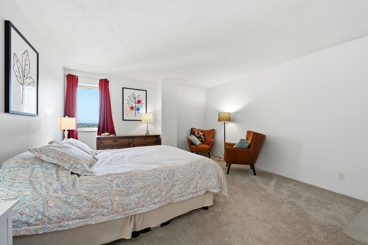 Spacious room featuring neutral carpeting, white walls, and a window with red drapes