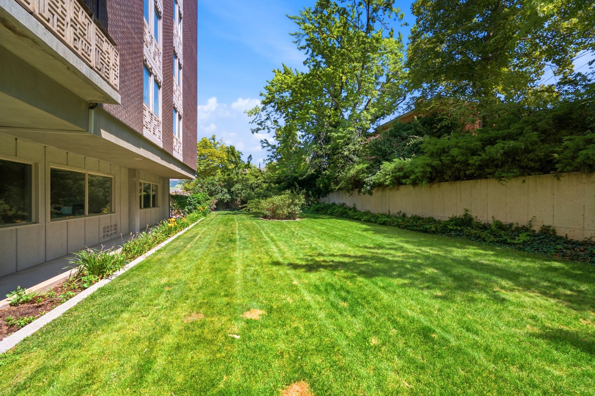 Expansive green lawn bordering a building facade featuring multiple windows