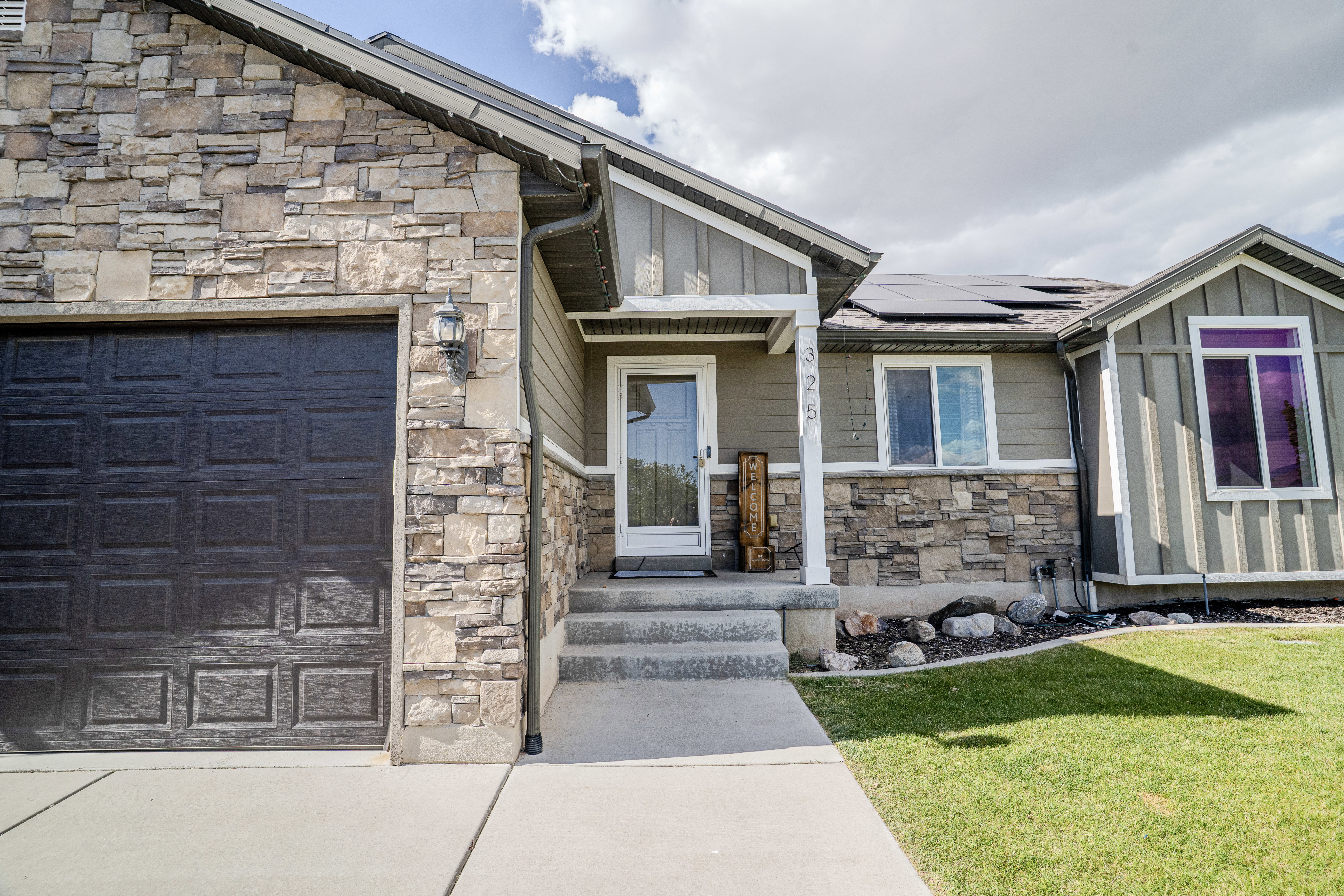 Stone veneer facade featuring a dark paneled garage door and an inviting front entry