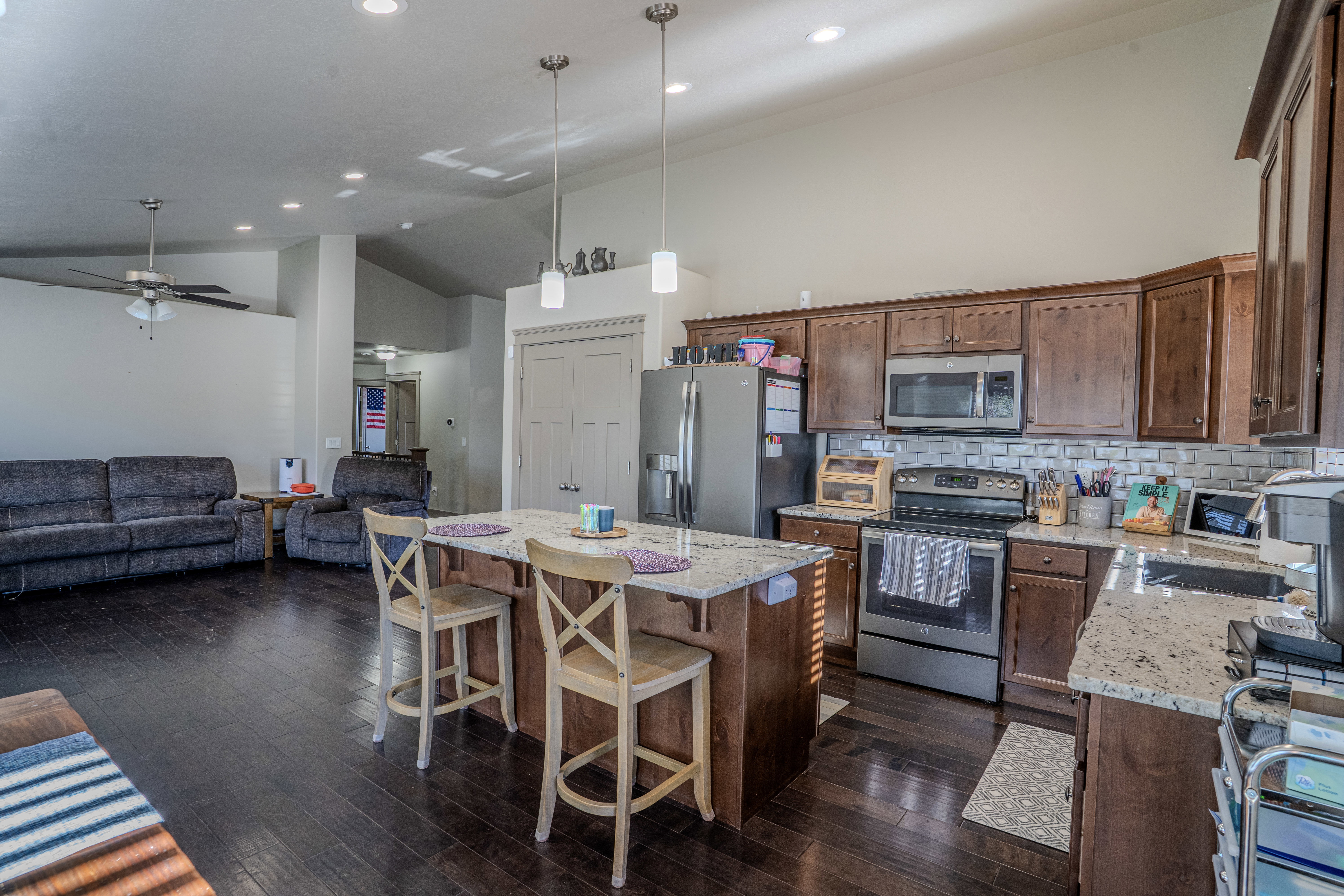 Open concept kitchen featuring granite countertops, wood-finish flooring, stainless steel appliances, a subway tile backsplash, and recessed lighting