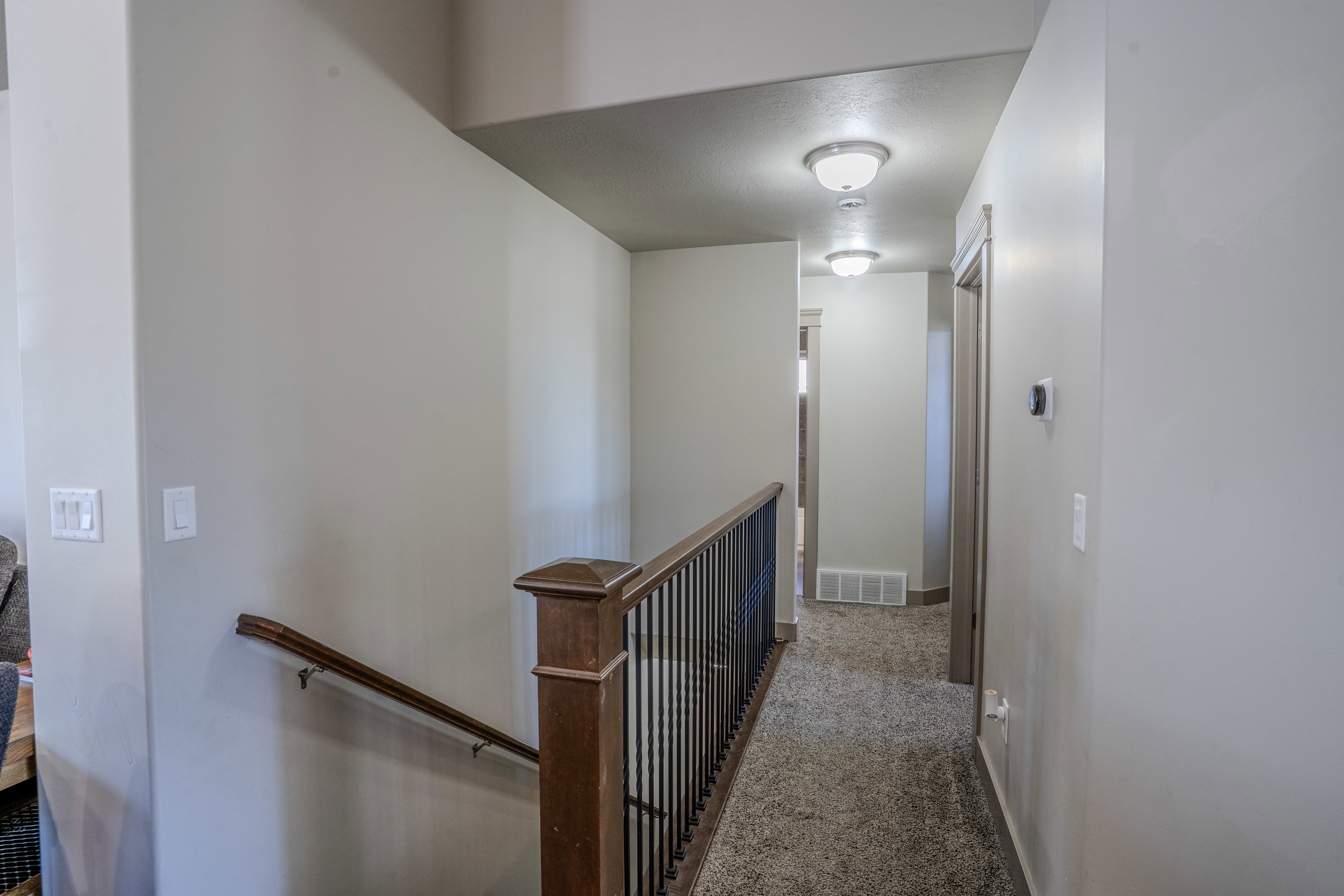 Hallway featuring textured carpeting and flush-mount ceiling lights