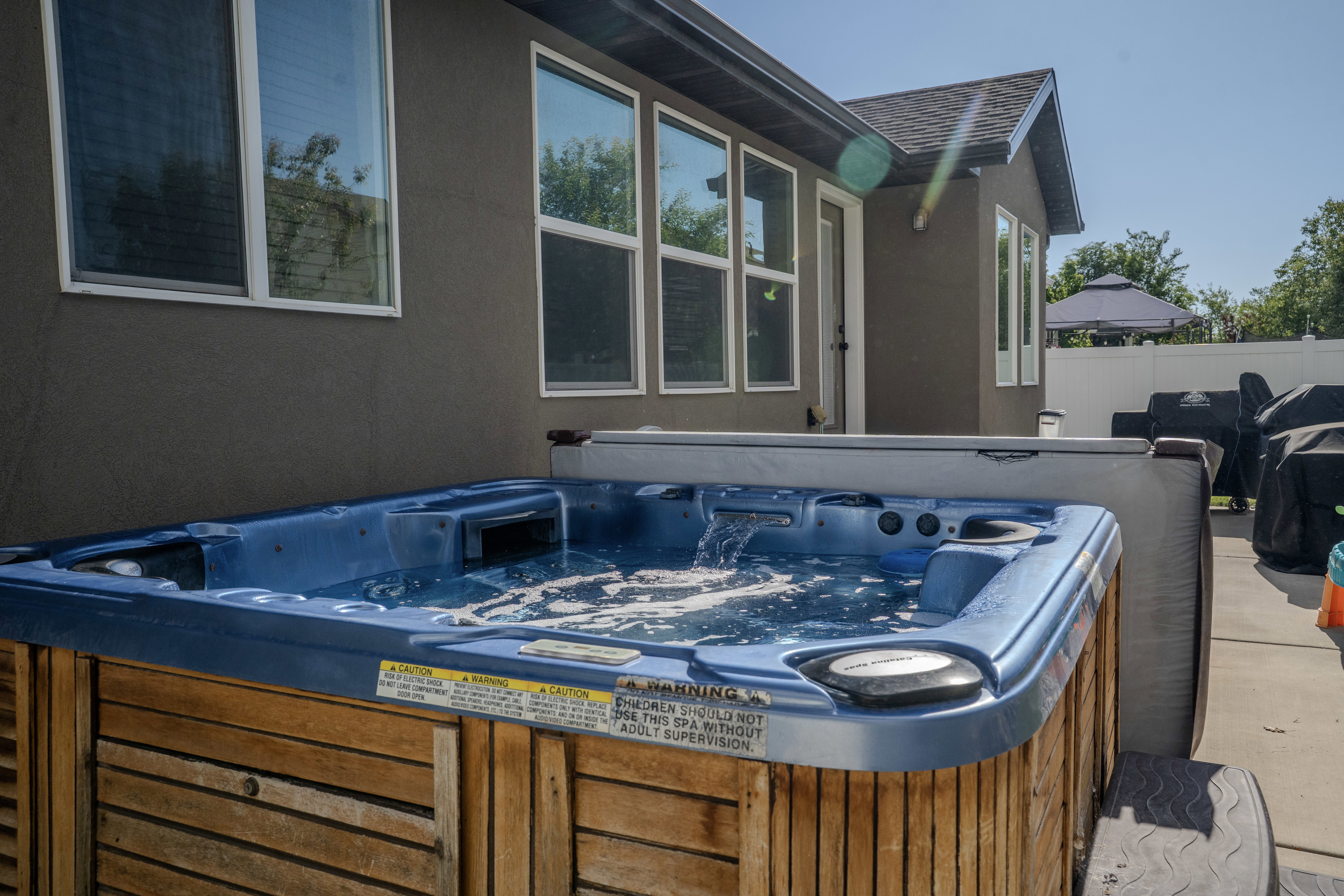 Outdoor spa with a wood-finish exterior, bubbling water, and a hard cover