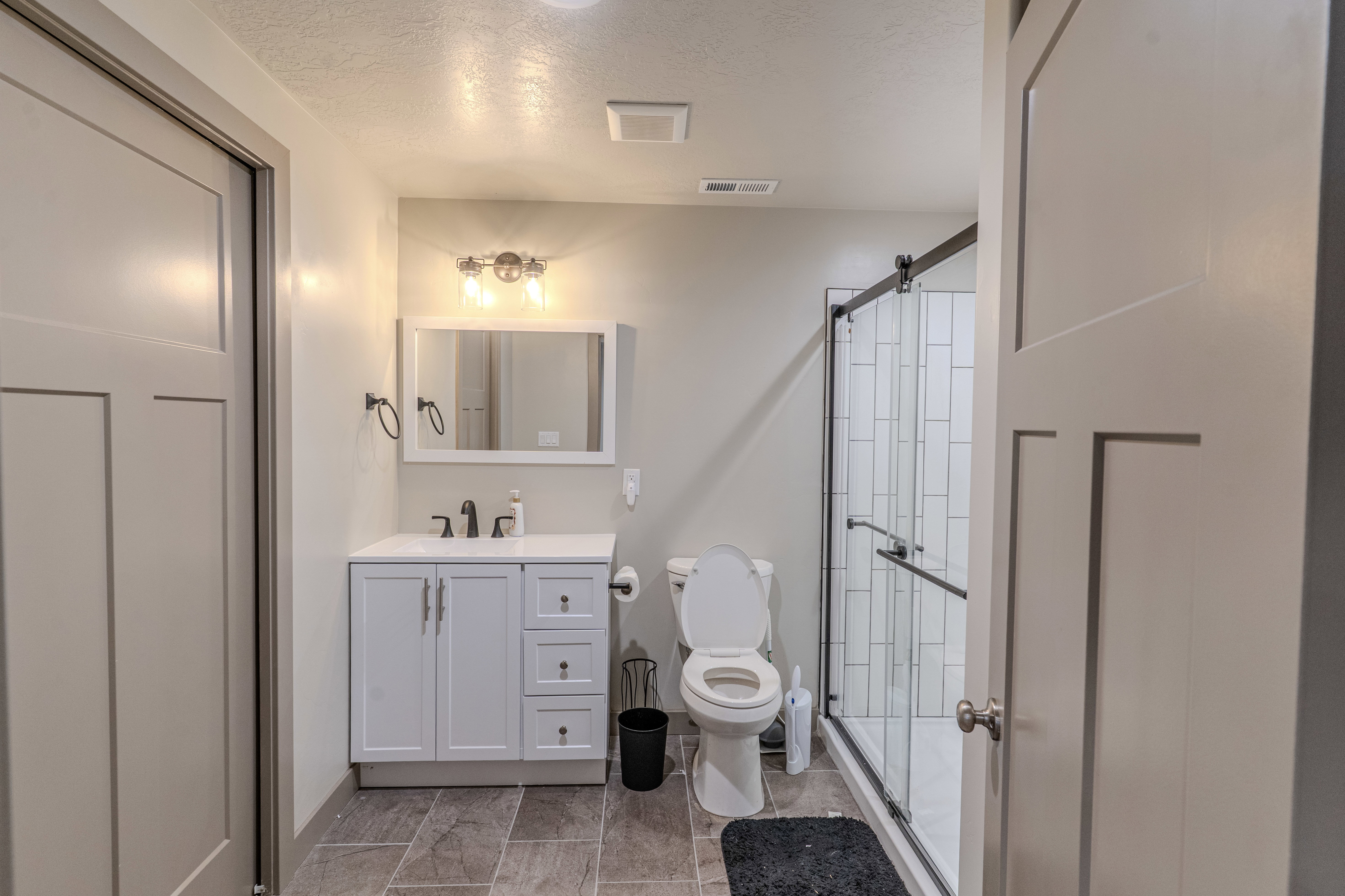 Contemporary bathroom featuring a white vanity with a rectangular sink, a framed mirror, and a three-light vanity fixture