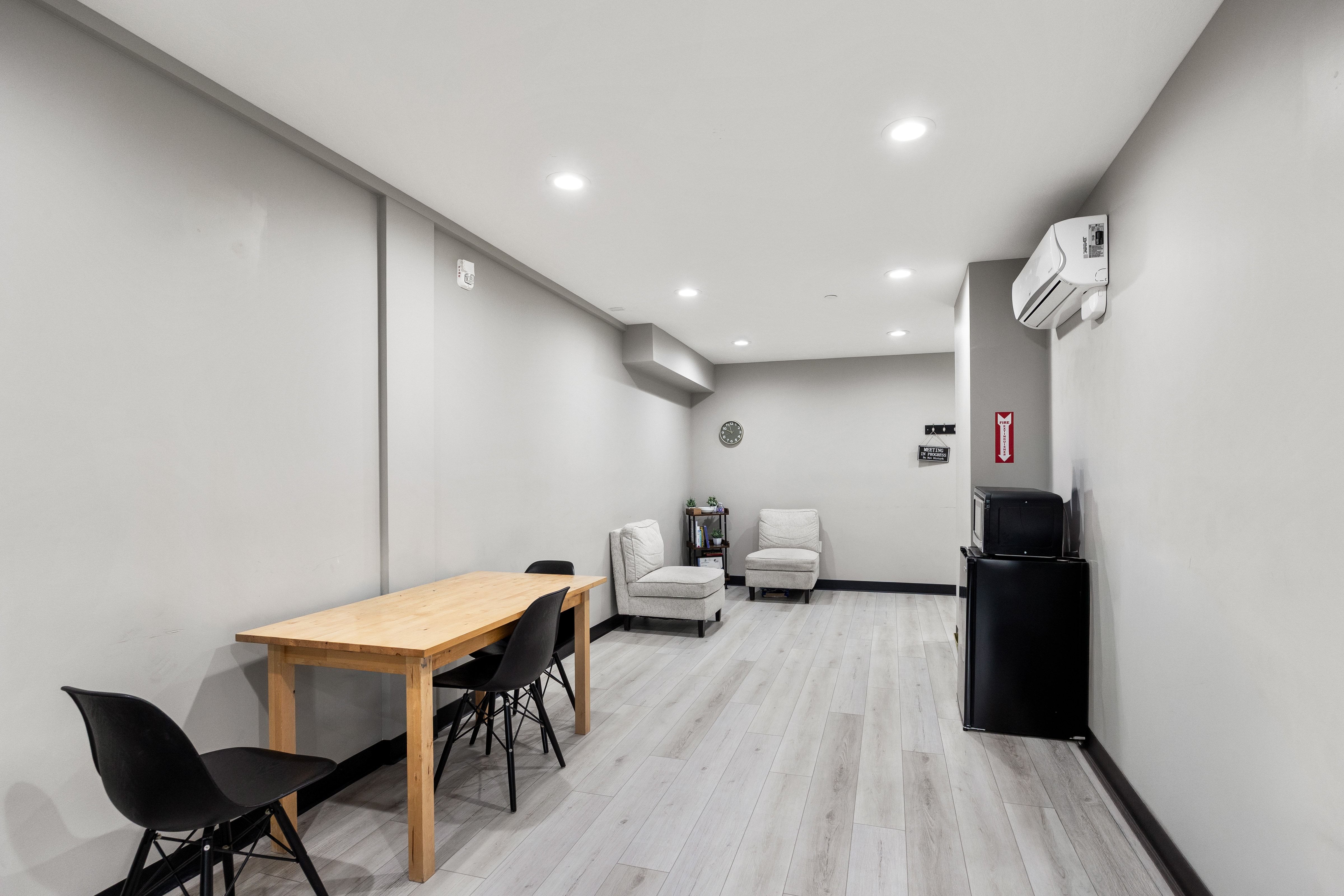 Spacious room featuring light wood-finish flooring, recessed lighting, and a wall-mounted air conditioning unit